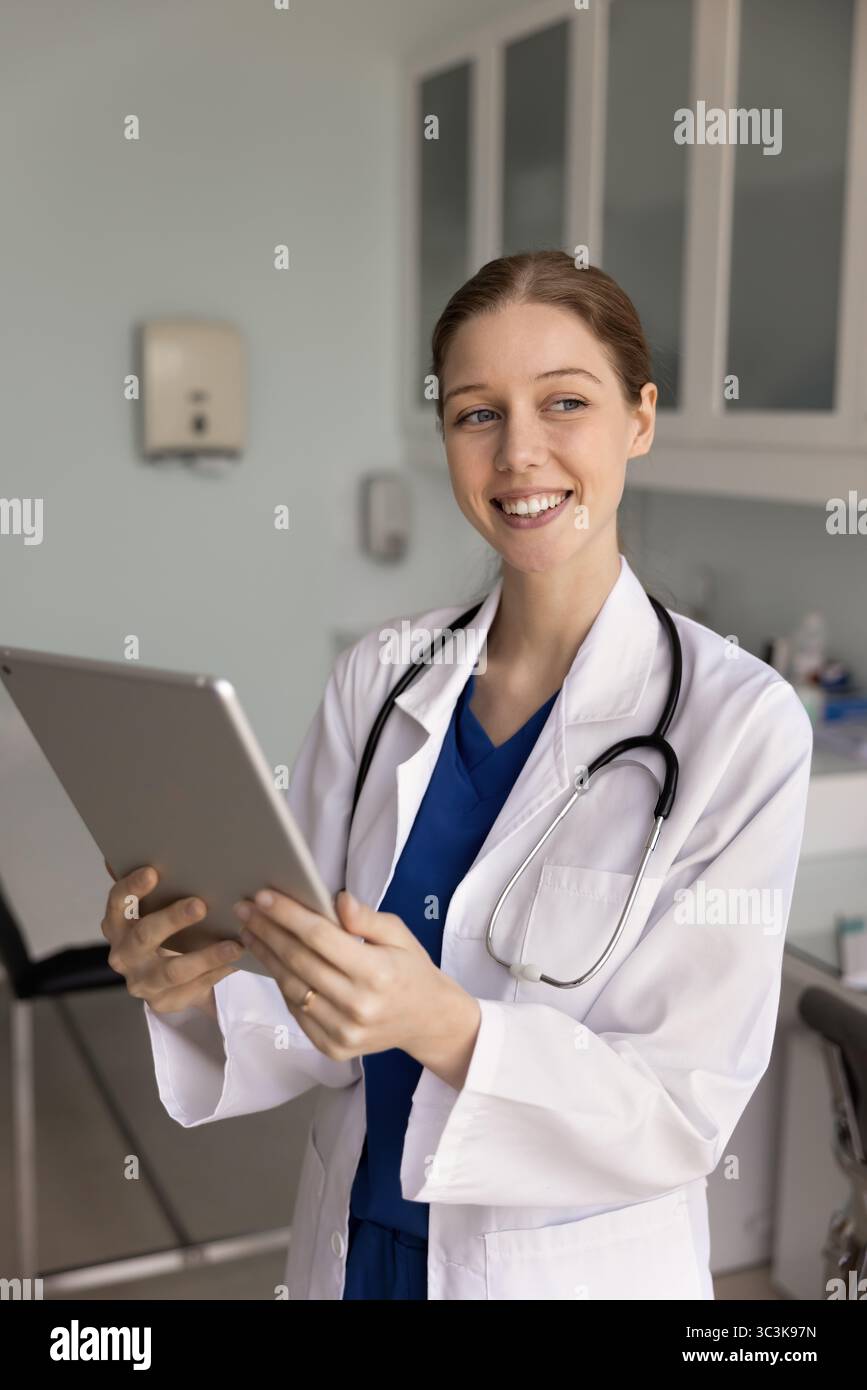 Positive female doctor using digital tablet for analyzing medical data Stock Photo