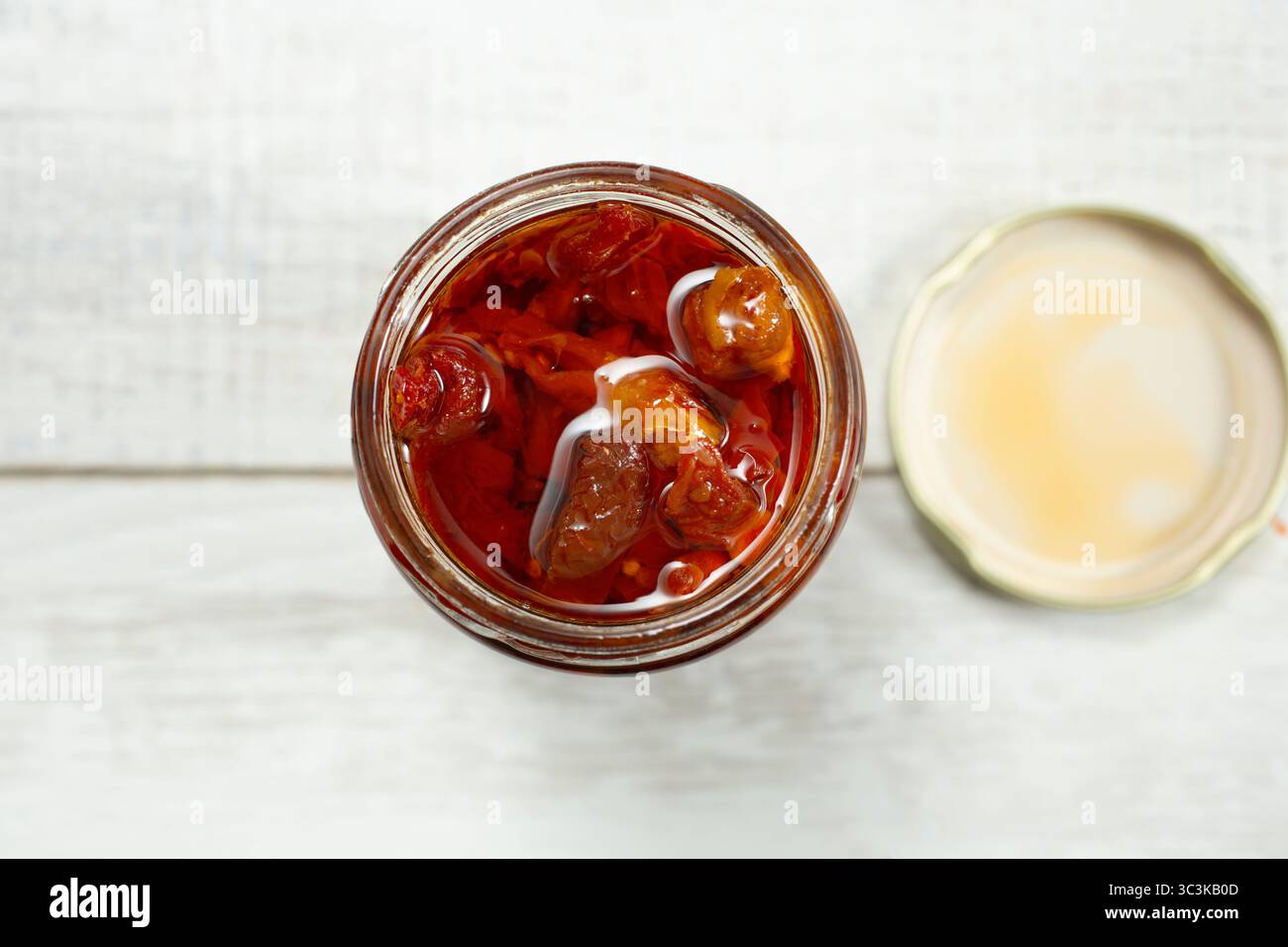 A top down view of an open jar full of sun-dried tomatoes. Stock Photo