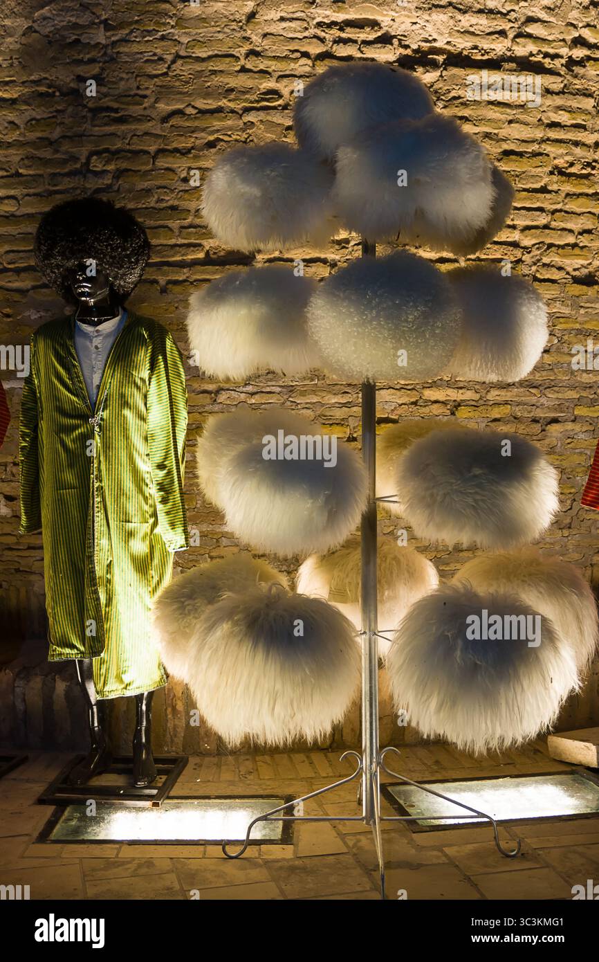 Khiva, Uzbekistan - July 12, 2024: Night photo of a display of traditional white fur hats in the city of Khiva, Uzbekistan, illuminated by warm lights Stock Photo