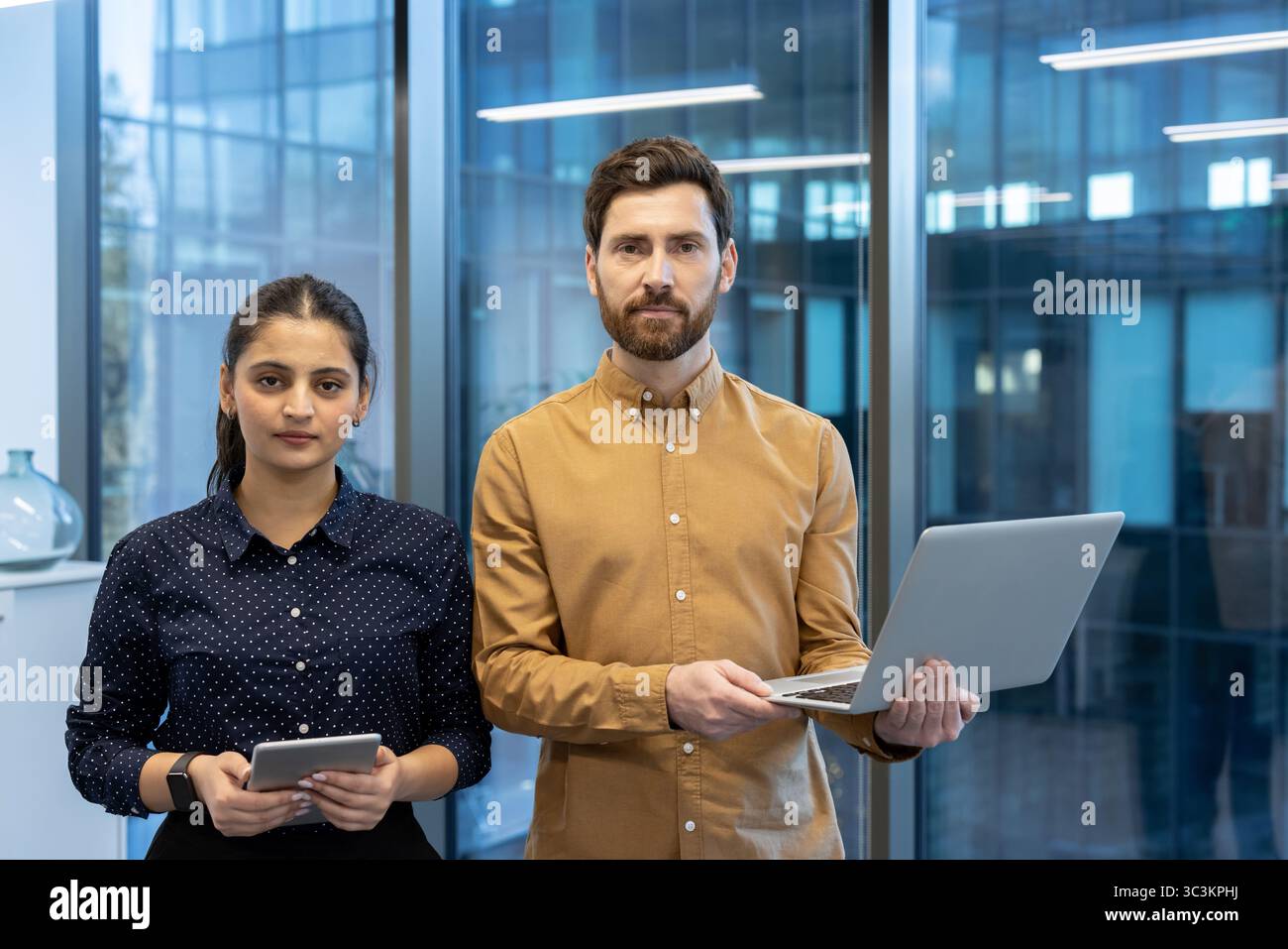 A diverse business team poses confidently in a modern office setting ...