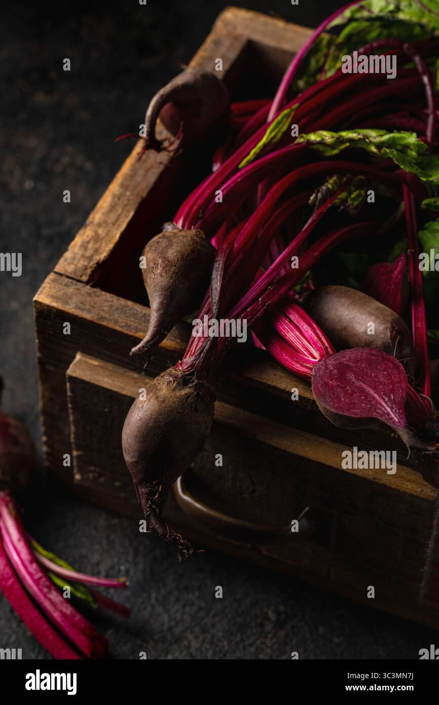 Fresh beetroots with vibrant green stems and leaves are displayed in a ...