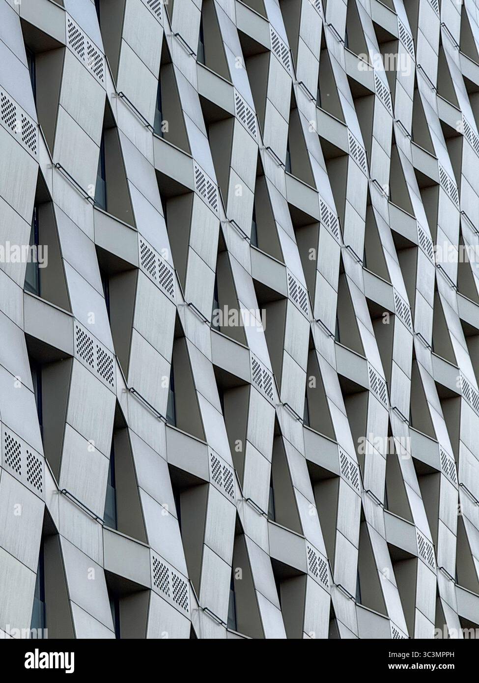 A close-up view of a modern city building facade, showcasing a geometric pattern of angled, overlapping panels. The dynamic design emphasizes contempo Stock Photo