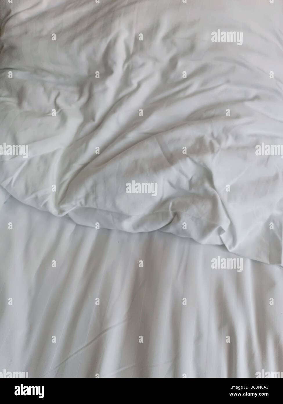 Empty wrinkled white bedding, close up, hotel, white pillows Stock Photo