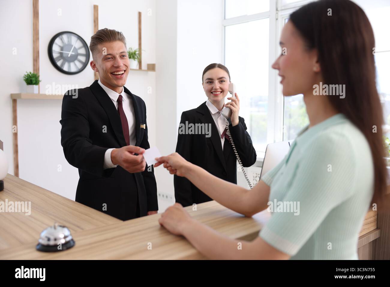 Receptionists and client at reception desk in hotel Stock Photo - Alamy