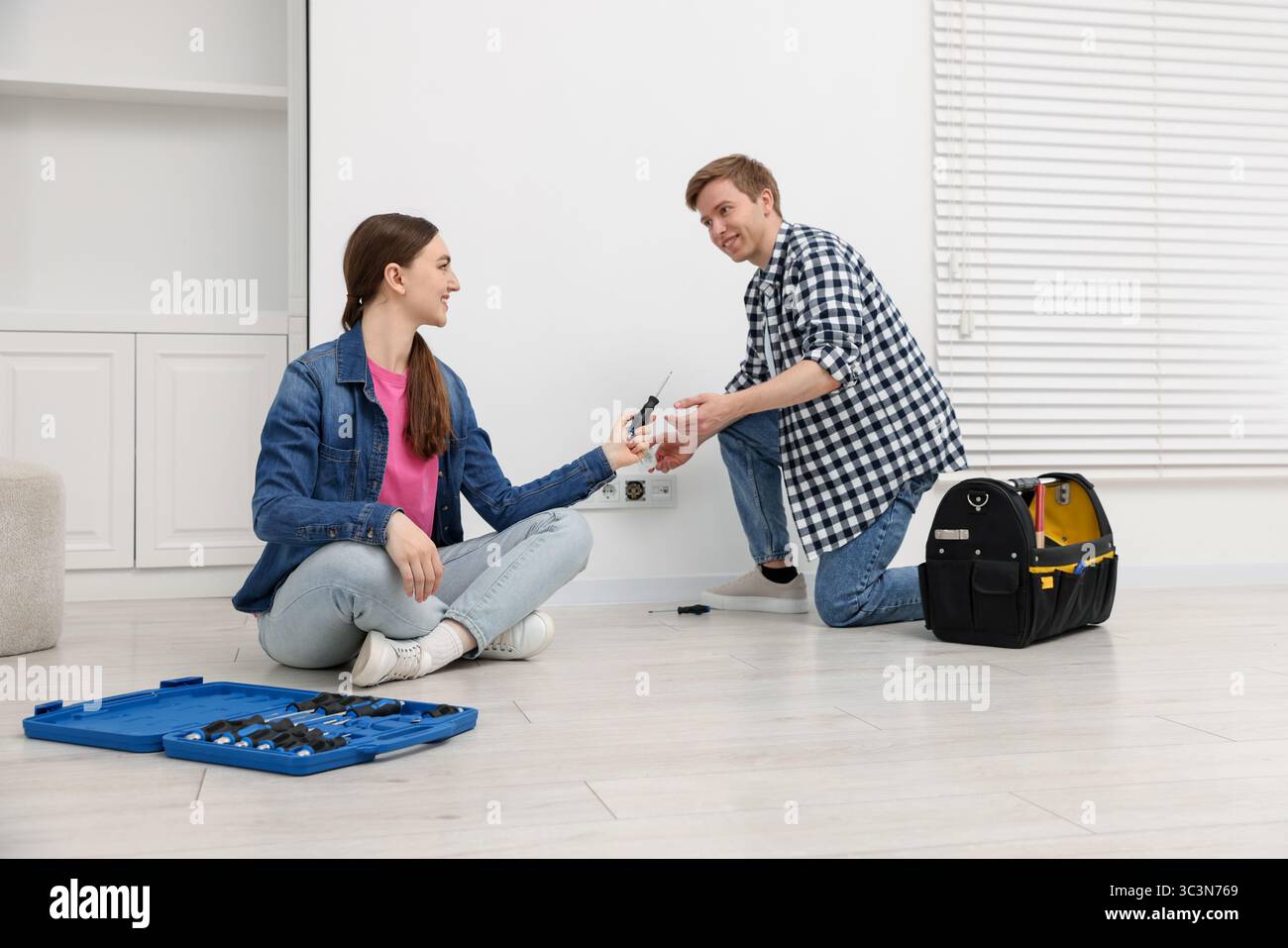 Couple with tools installing new socket at home Stock Photo
