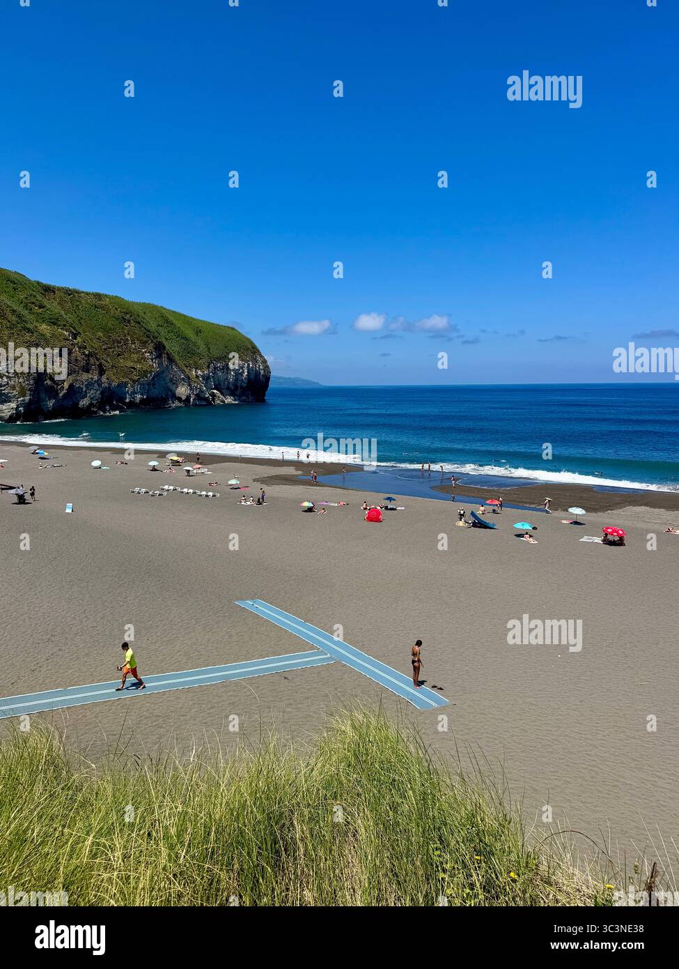 People relaxing on Santa Bárbara Beach with black volcanic sand and clear blue waters on São Miguel Island, Azores, Portugal. - Smartphone Captured Stock Image