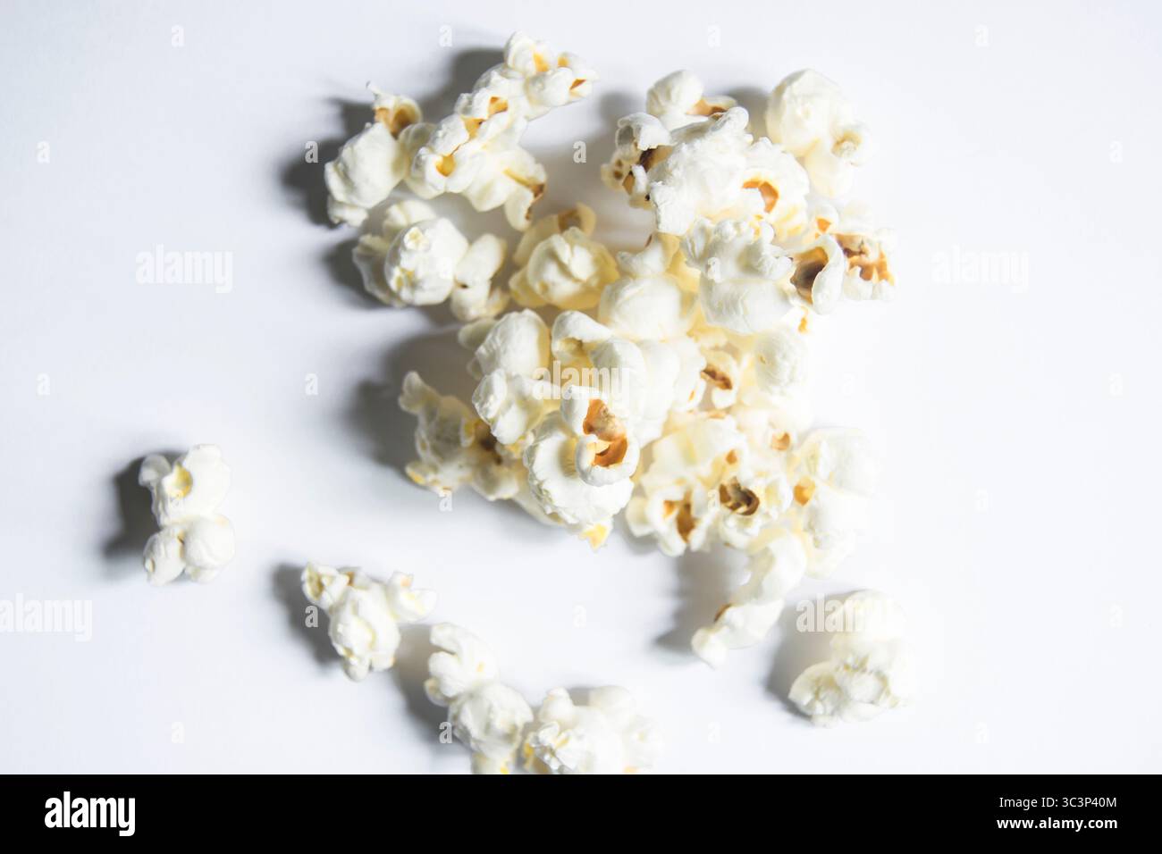 Freshly popped popcorn scattered across a with background Stock Photo