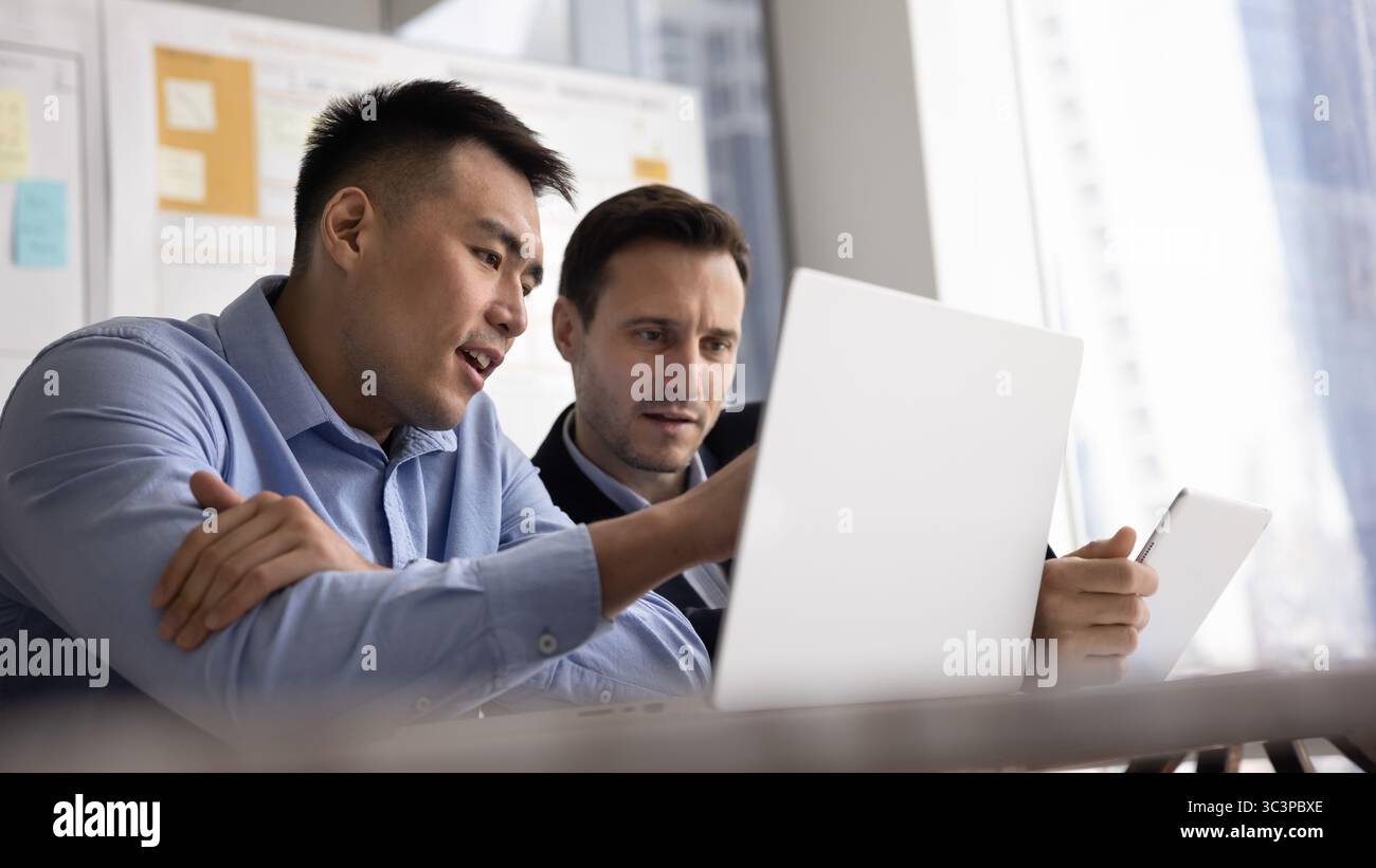 Multiracial focused teammates using digital tablet and laptop Stock Photo