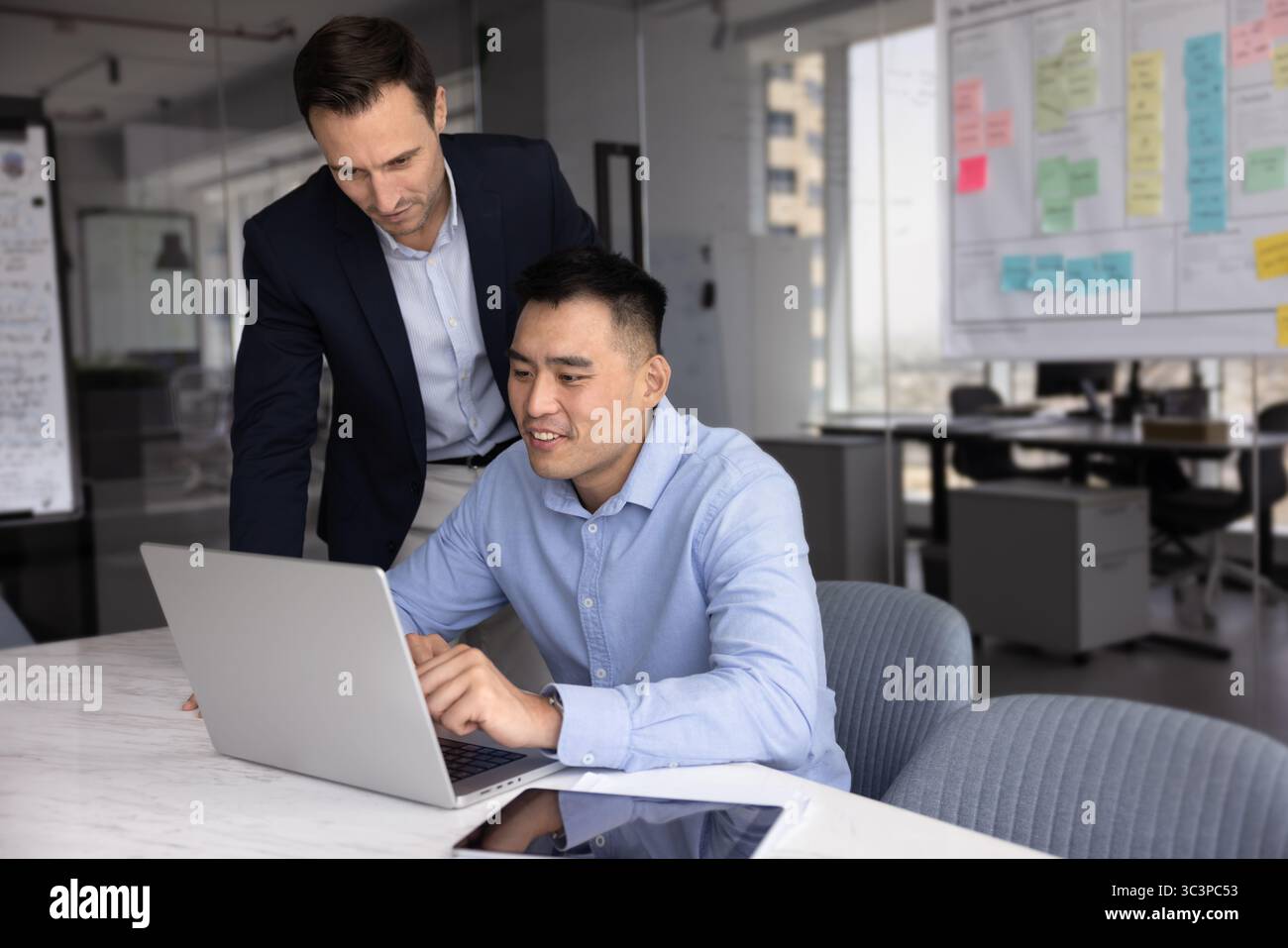 Two multiethnic employees using laptop in modern workplace Stock Photo