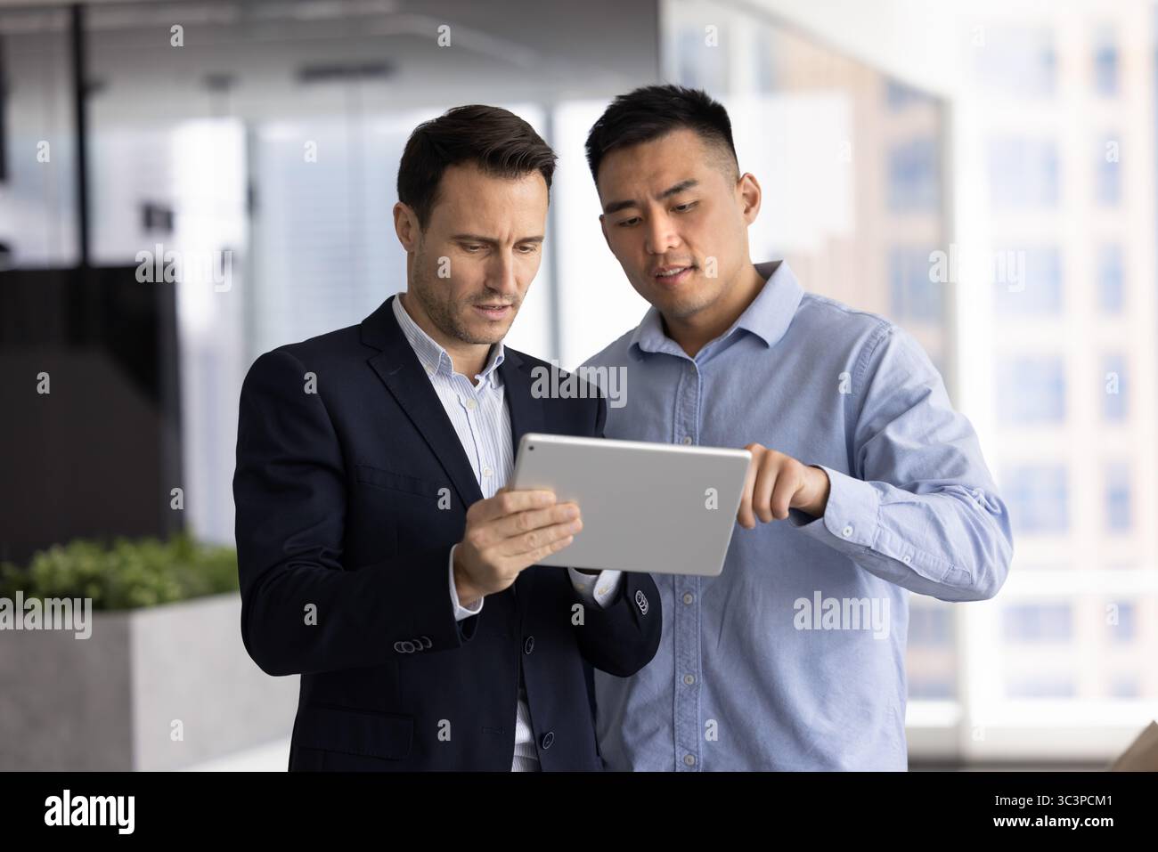 Two diverse professional men working together in office using tablet Stock Photo