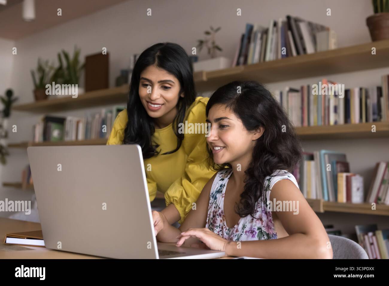 Two attractive Indian workmates using laptop in modern office Stock Photo