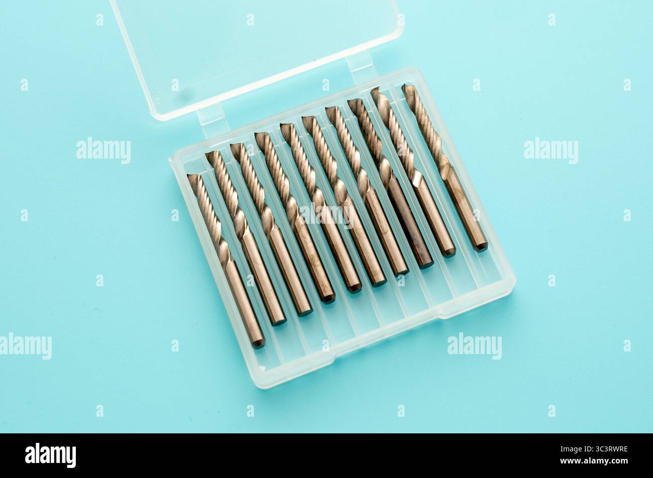 A set of metal milling cutters neatly arranged in a transparent plastic case on a blue background. Ideal for use with milling machines in various mach Stock Photo
