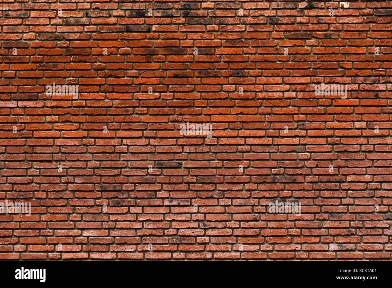 Weathered red brick wall with irregular texture and natural color variation Stock Photo