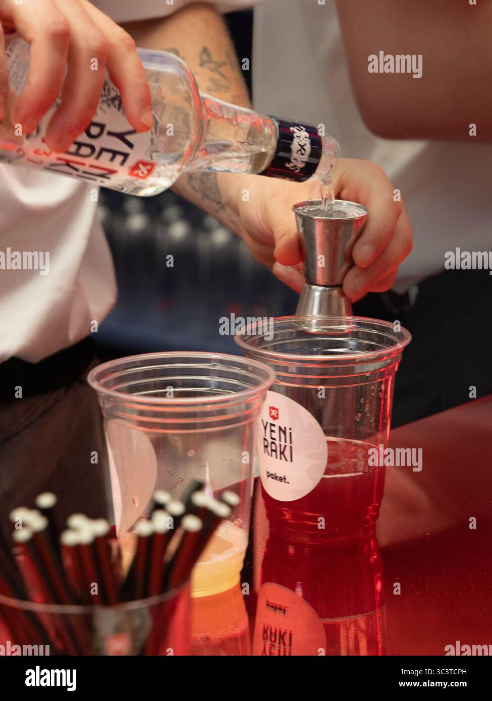 Yeni Raki stand at the National Geographic Traveller food festival 20th July 2025 .Close up focussing on hands pouring Yeni Raki. Portrait shot Stock Photo