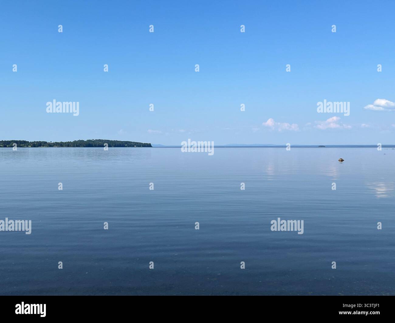 The expansive lake mirrors the vibrant blue sky, creating a sense of tranquility and calm. - Smartphone Captured Stock Image