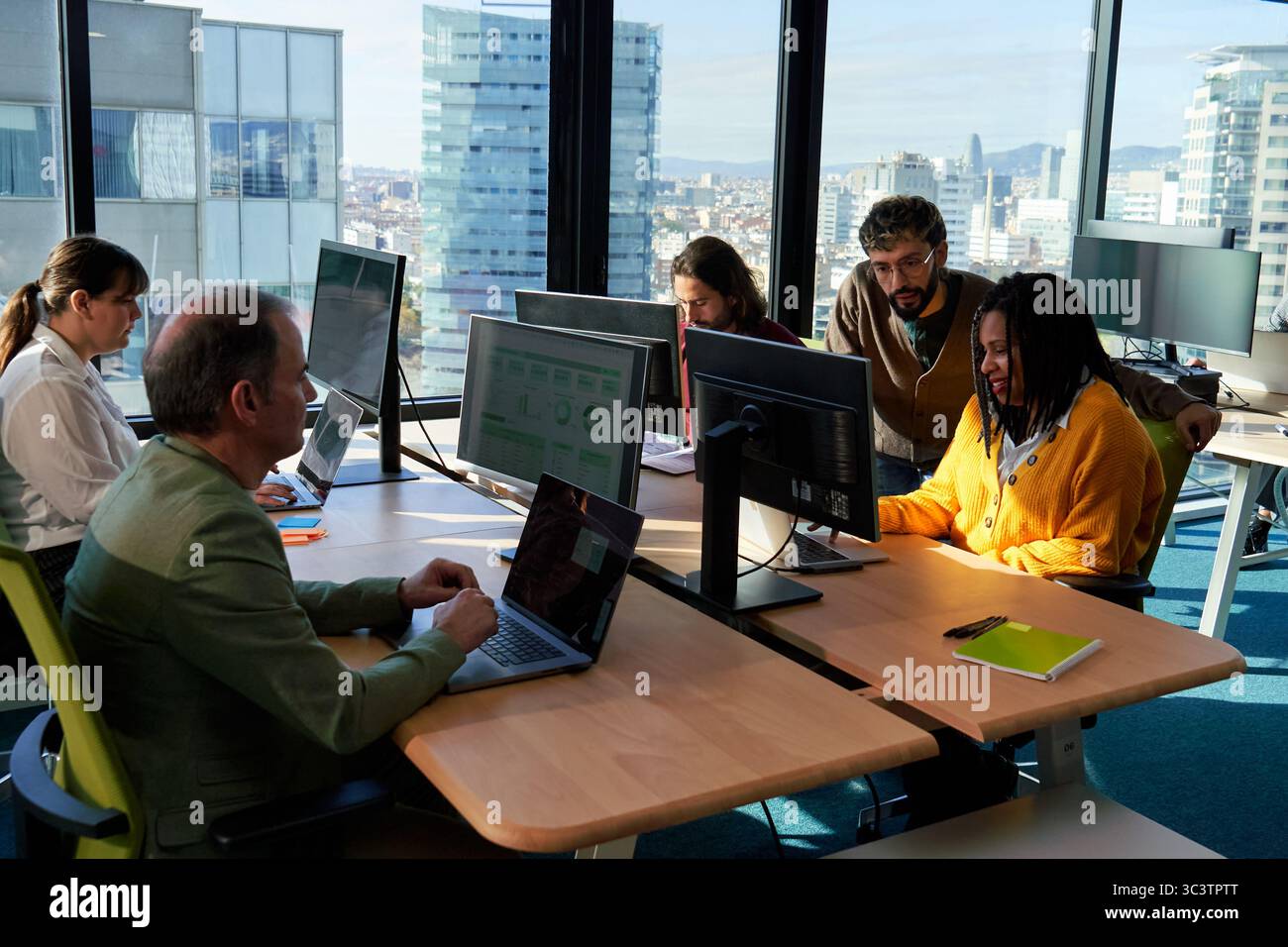 Work colleagues working on computers in modern office with city view. Stock Photo
