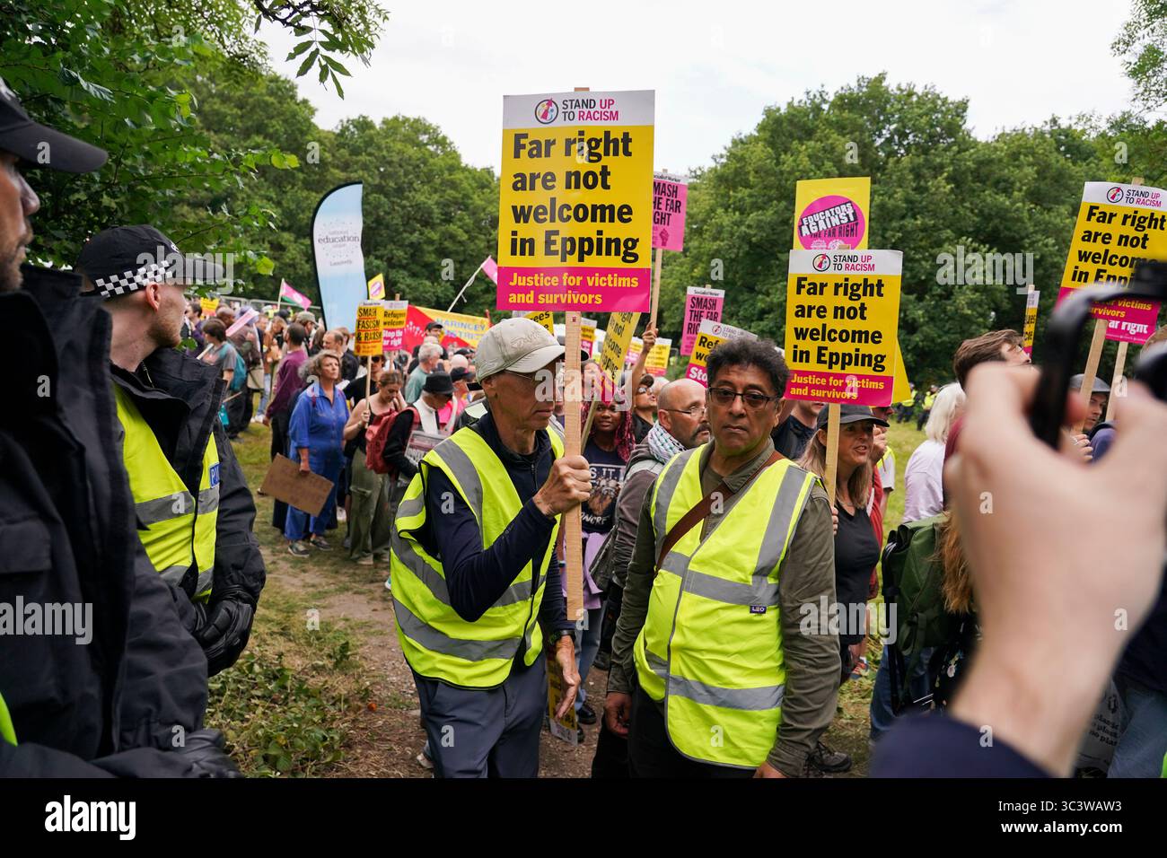 Demonstrators hold placards and banners as they leave a protest outside the Bell Hotel in Epping, near London, Sunday, July 27, 2025.(AP Photo/Alberto Pezzali) Stock Photo