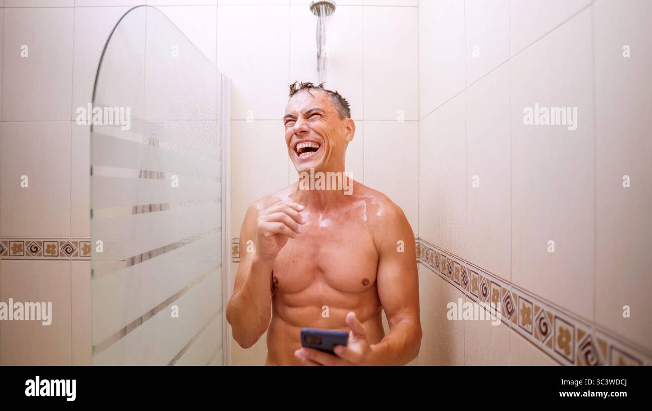 Man laughing while using smartphone in shower Stock Photo