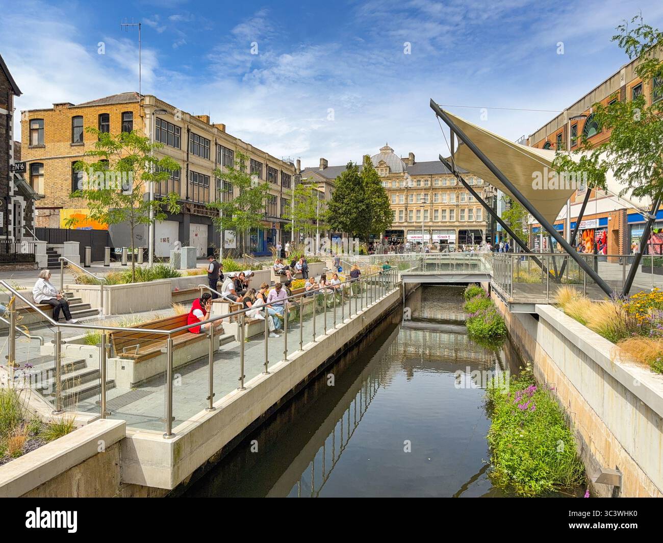 Cardiff, Wales, UK - 16 July 2025: Scenic landscape view of people resting on seats in the Canal Quarter in Cardiff city centre. - Smartphone Captured Stock Image