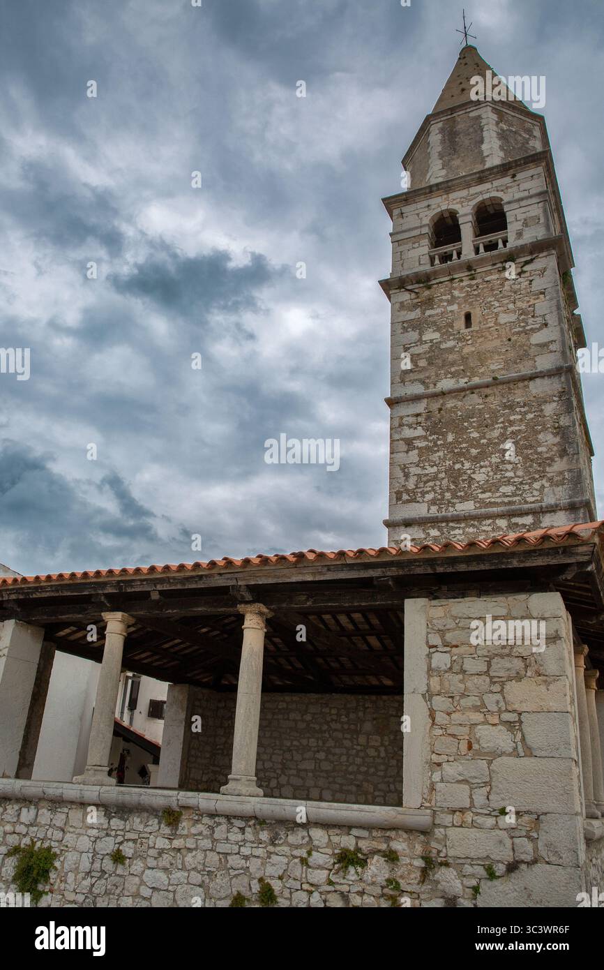 Ancient limestone campanile with arched bell tower above historic stone ...