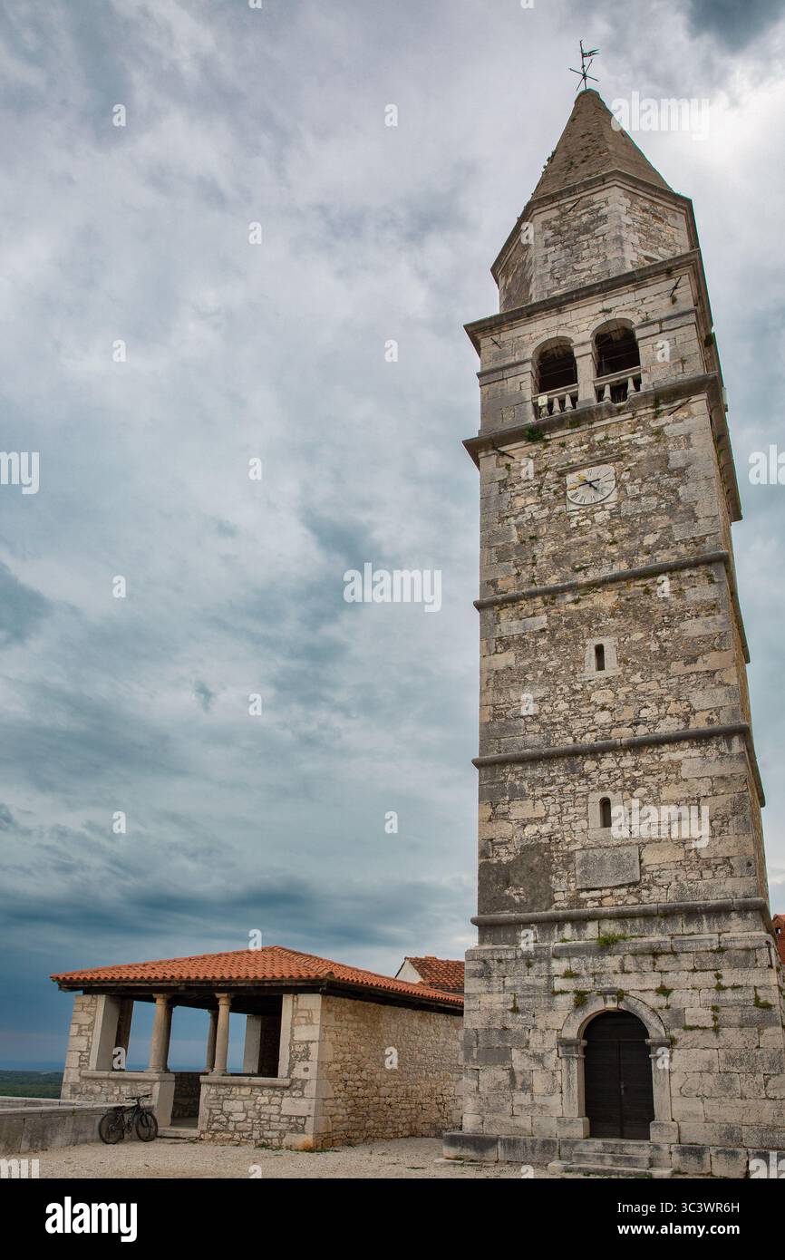 Ancient limestone campanile with arched bell tower above historic stone ...
