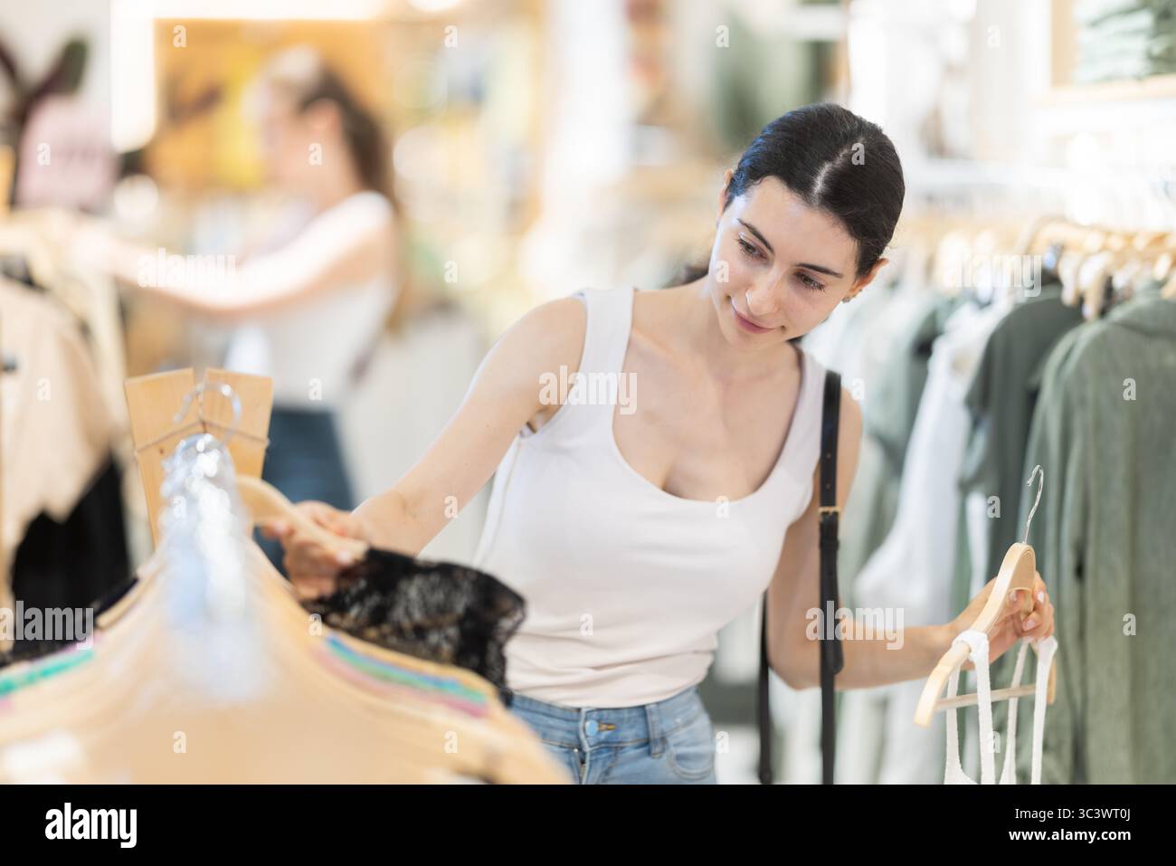 Girl customer chooses singlet blouse in branded store Stock Photo