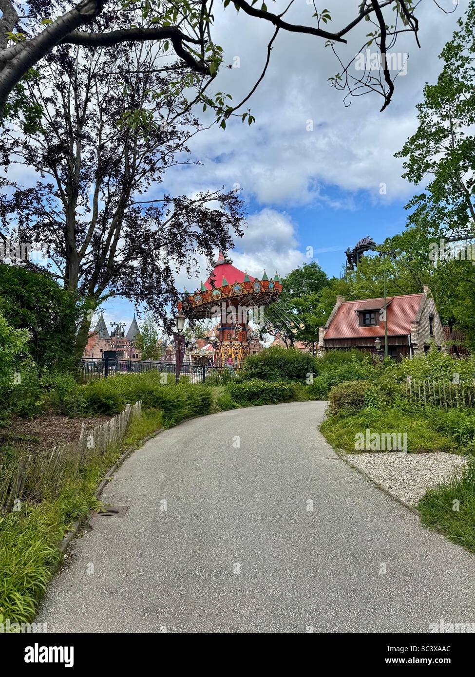 Scenic pathway leading to colorful theme park structures at Hansa Park in Germany on a partly cloudy day. - Smartphone Captured Stock Image
