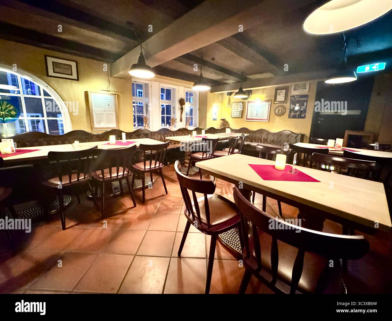 Interior of Brauberger brewery restaurant in Lübeck, Germany, showing traditional German pub atmosphere with wooden furniture, candlelight, and histor - Smartphone Captured Stock Image