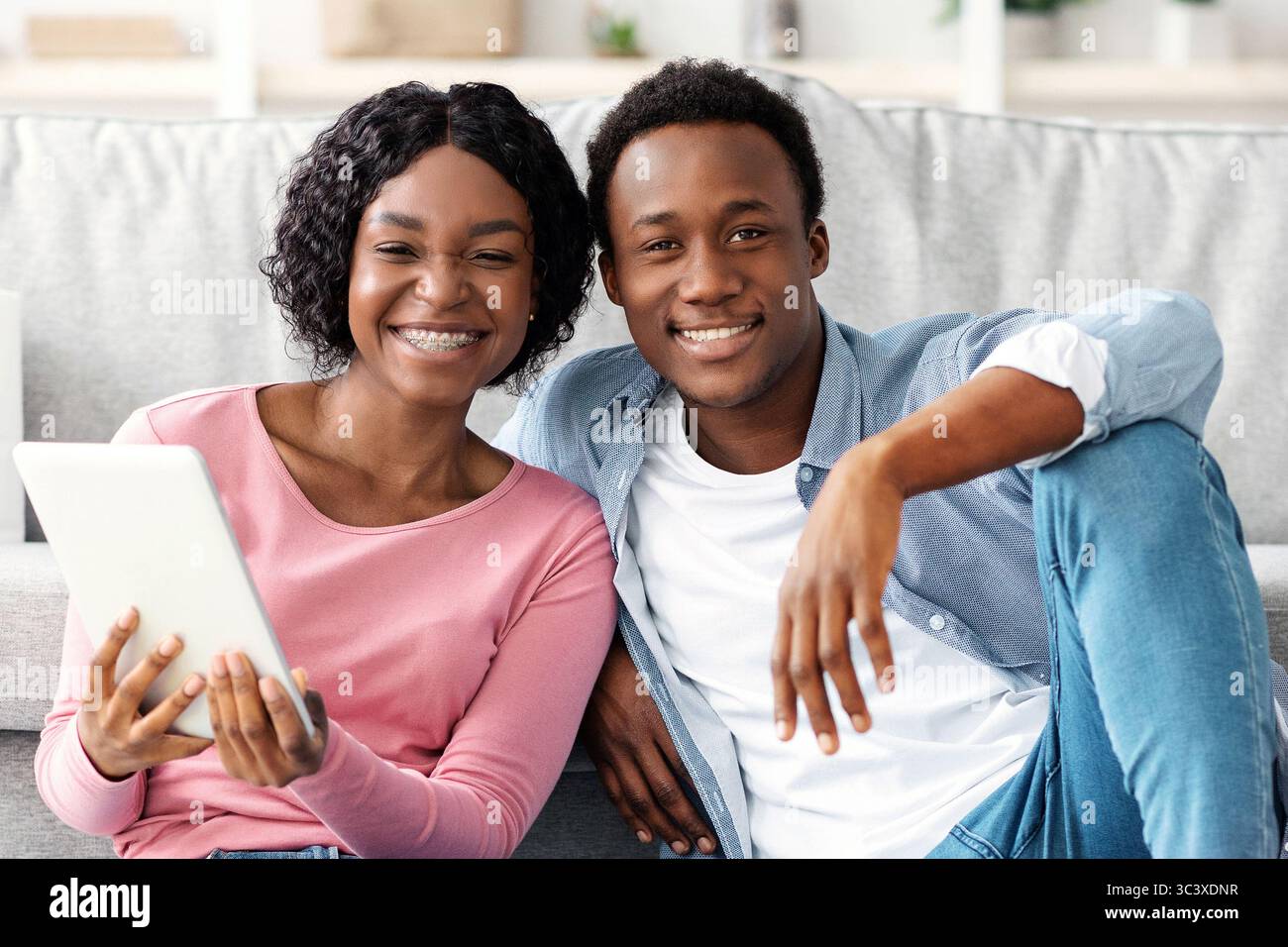 Black couple with cleaning tools resting, using digital tablet Stock Photo