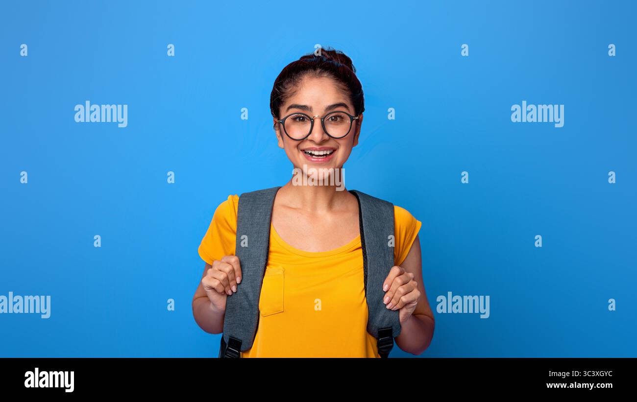 Happy indian female student wearing backpack and eyeglasses Stock Photo