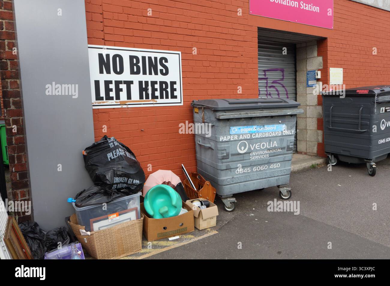 No bins left here, sign on brick wall, Sheffield UK behind charity shop Stock Photo