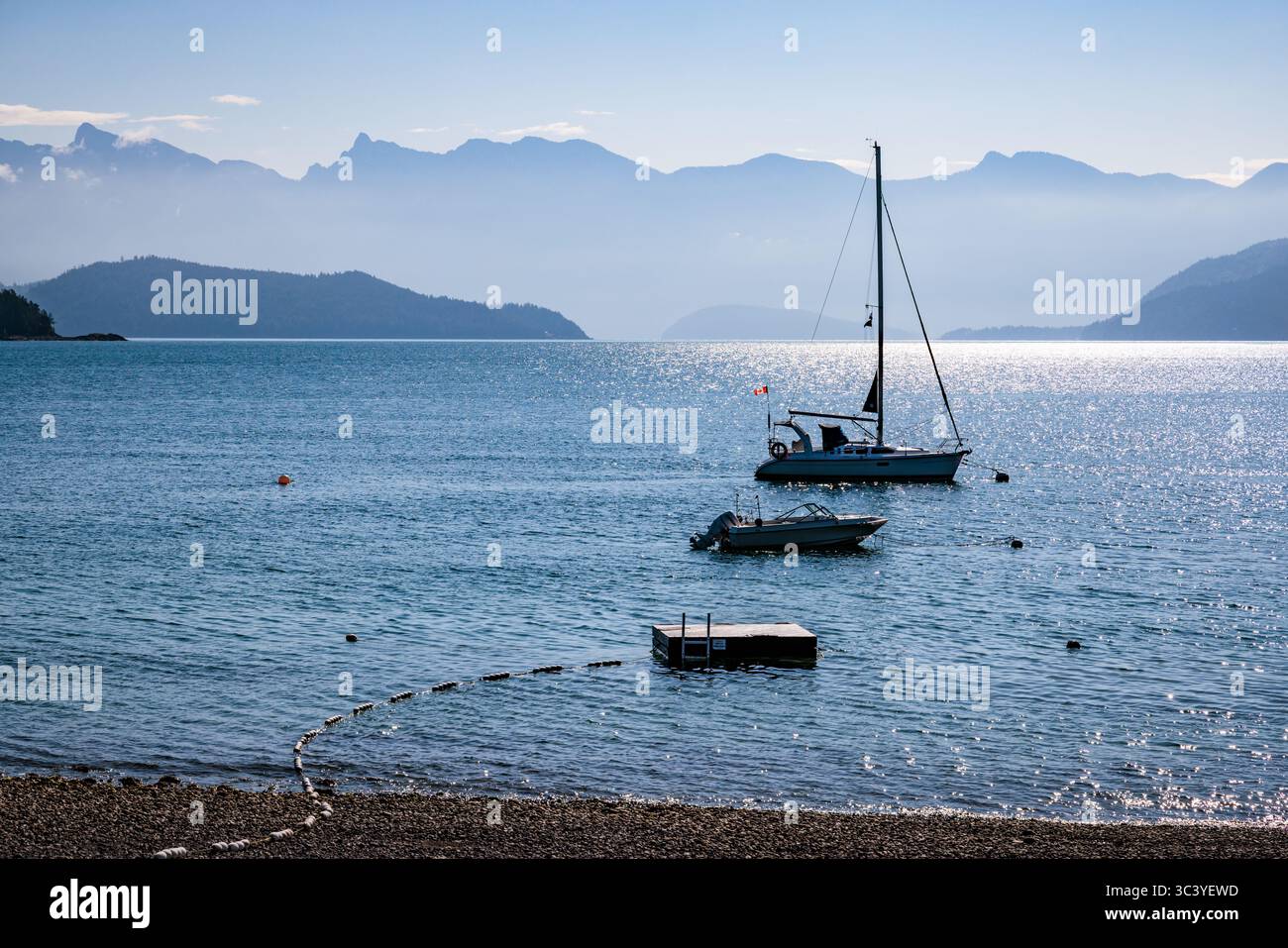 Two boats moored on the shoreline at Gibsons in British Columbia, Canada, overlooked by hazy mountains from Vancouver. Stock Photo