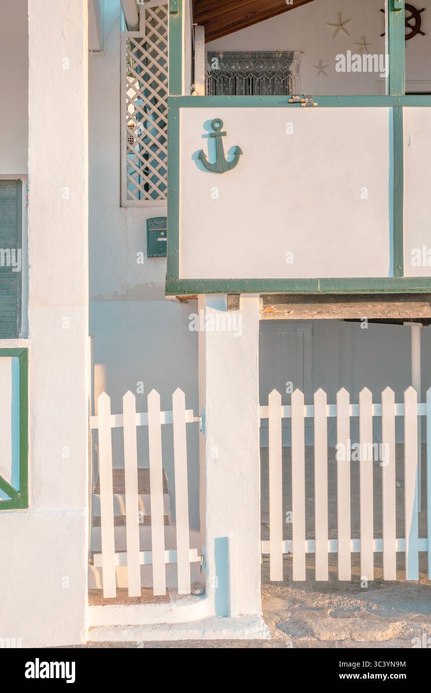 Nautical Beach House With Anchor Decoration And White Picket Fence. Mediterranean Coastal Architecture, Turquoise Trim, Seaside Cottage, Maritime Them Stock Photo