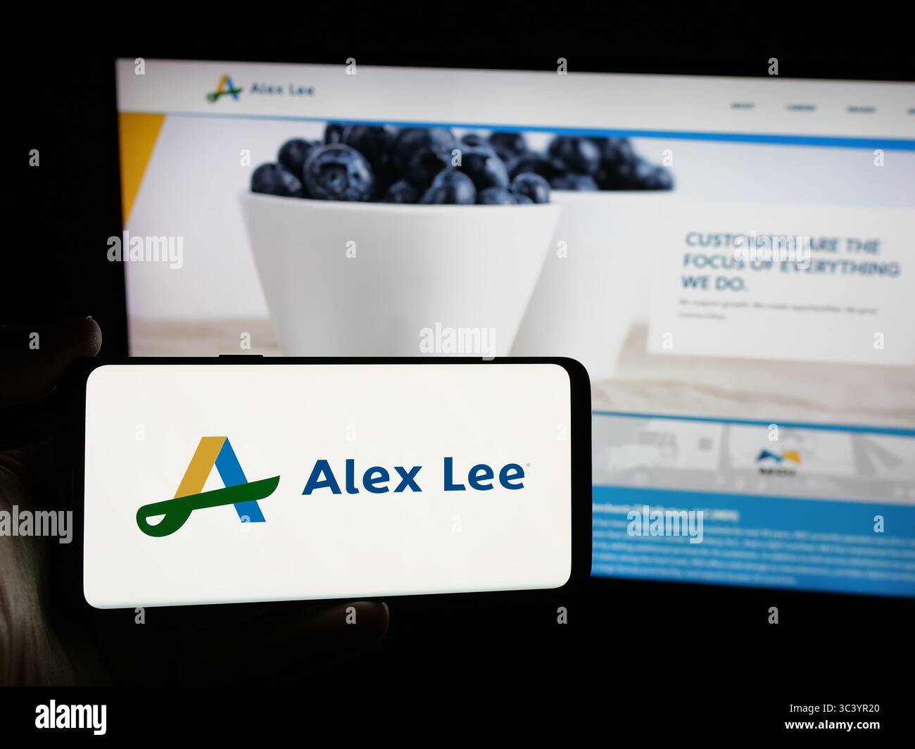 Stuttgart, Germany - 06-05-2025: Person holding smartphone with logo of US grocery wholesale company Alex Lee Inc. on screen in front of website. Stock Photo