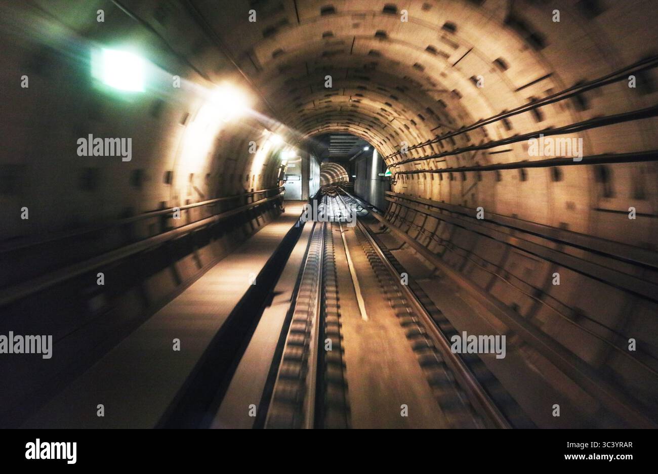 Long exposure captures the dramatic motion of a metro train moving through a tunnel. Bright lights and blurred lines create a sense of speed and depth Stock Photo