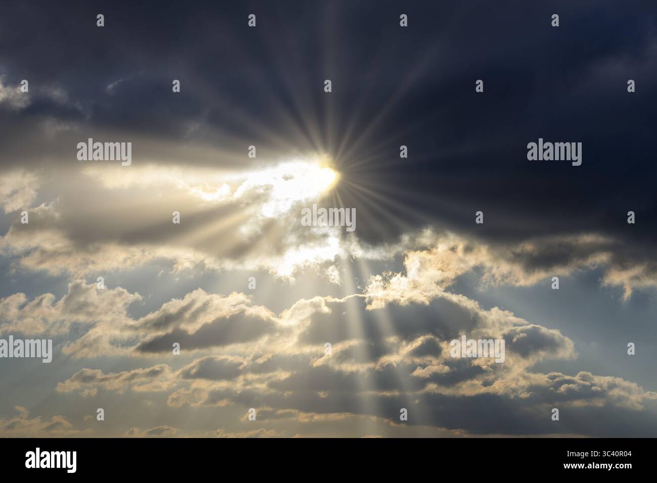 Dramatic rays of sunshine break through dark clouds in the sky, Baden-Wuerttemberg, Germany Stock Photo