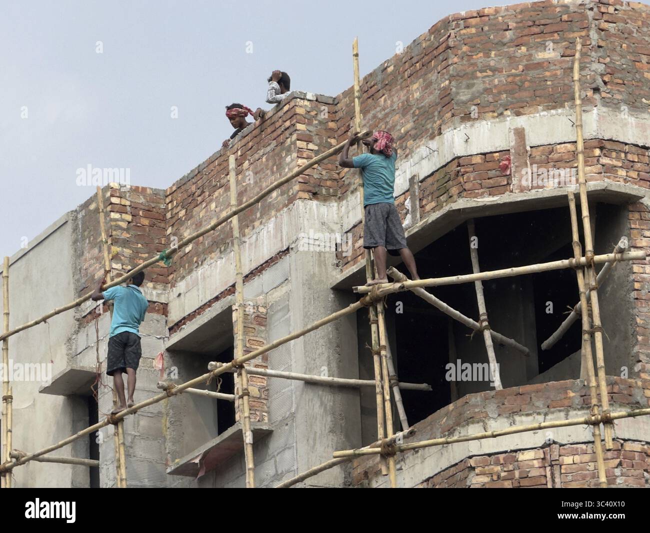 Construction workers on scaffolding working on a brick building. The ...
