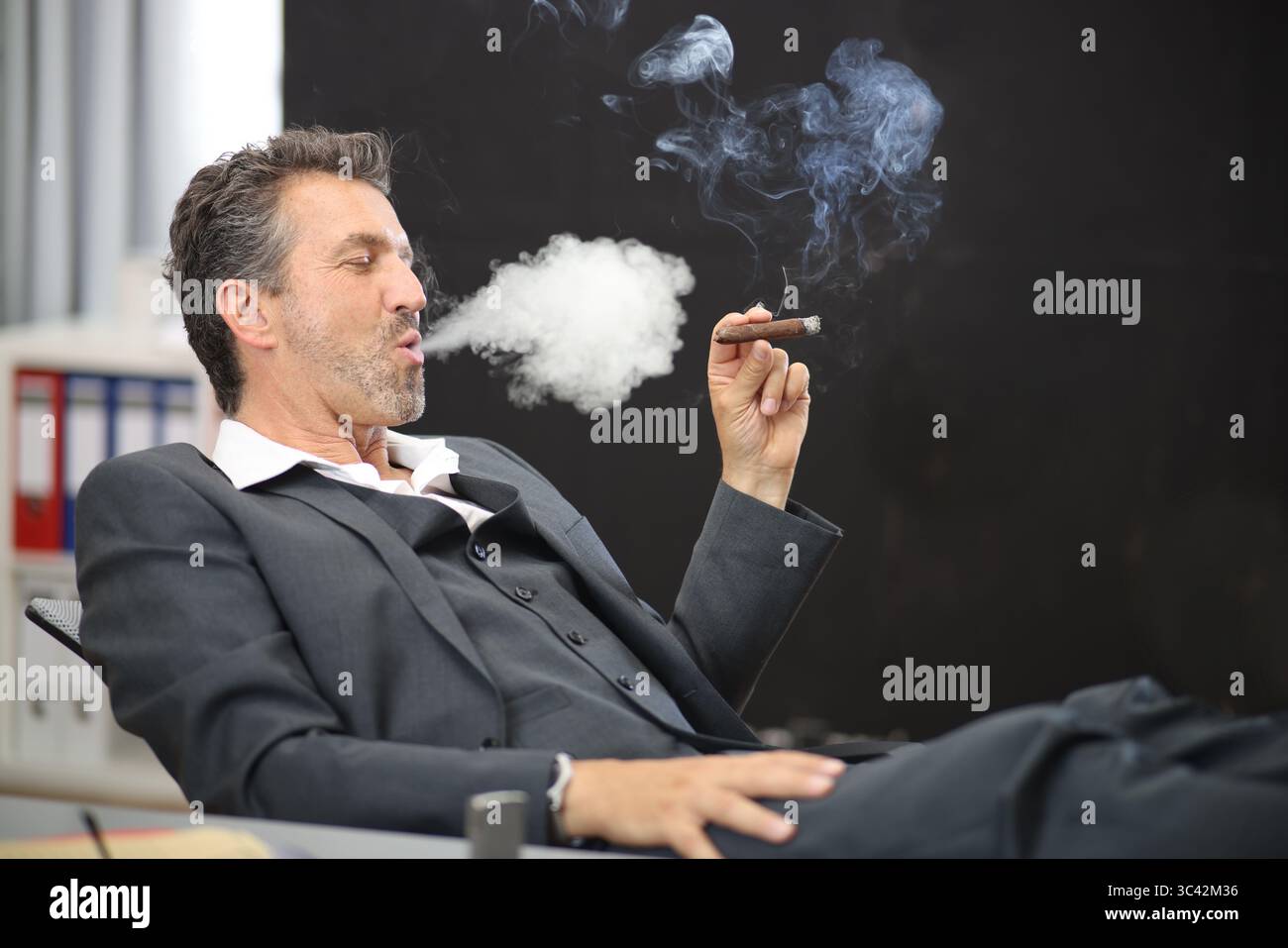 cigarette office Man in office smoking with cigarette and feet on the table Stock Photo
