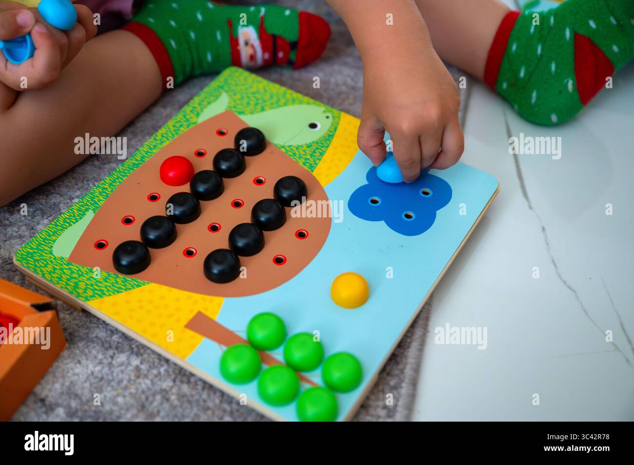 Toddler sorting colorful pins by matching them to images, fostering ...