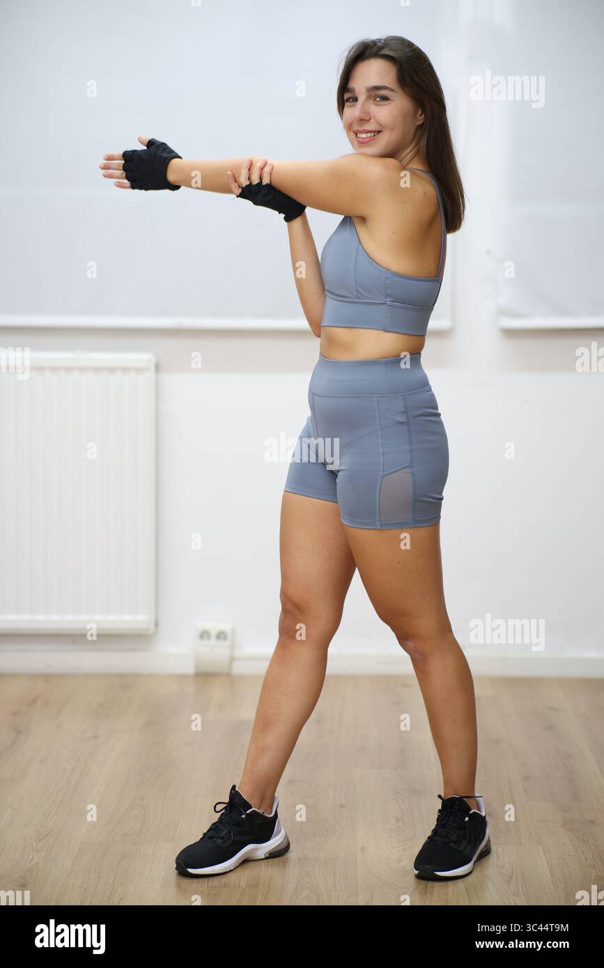 young smiling woman stretching against white background Stock Photo