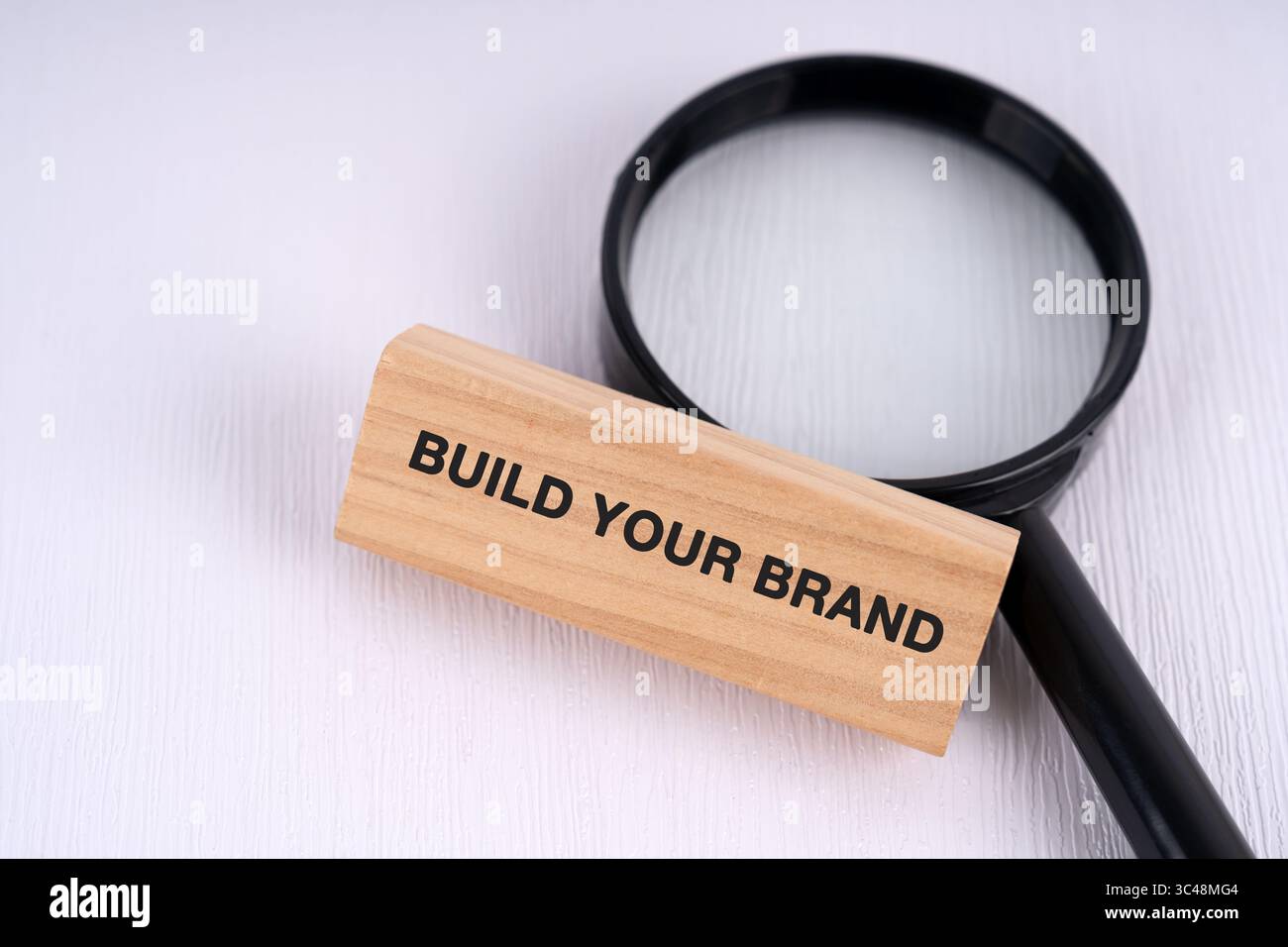 Magnifying glass and text build your brand text on wooden block business concept Stock Photo