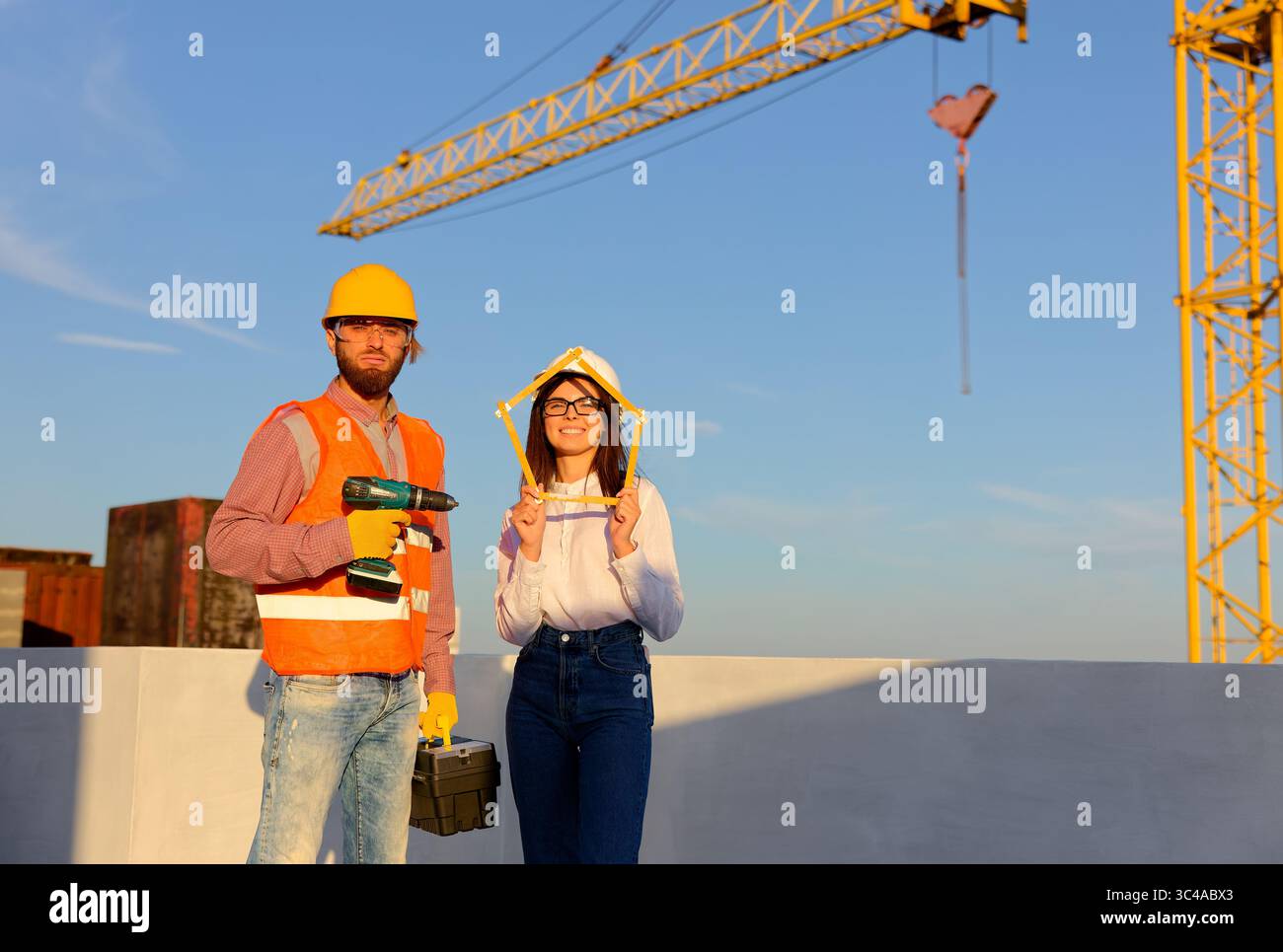 Construction workers are posing at building site holding folding ruler ...
