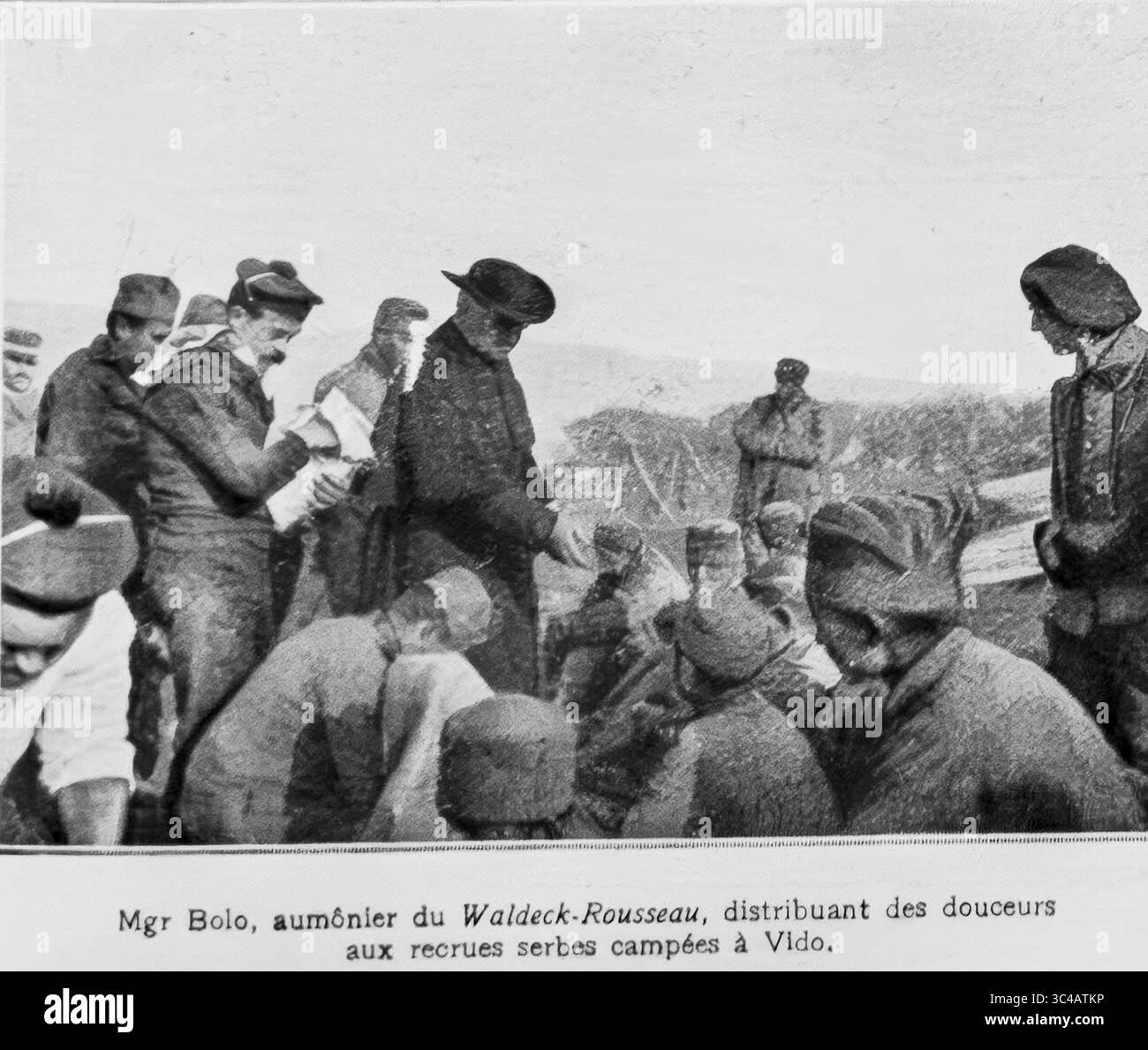 Monsignor Bolo, chaplain of the French cruiser Waldeck-Rousseau, distributing sweets and comfort to Serbian recruits encamped on the island of Vido, near Corfu, during World War I. The scene, published in LíIllustration in 1916, illustrates humanitarian aid offered by the French Navy to exiled Serbian forces recovering after retreating through Albania. A rare image of wartime morale and clergy involvement. Stock Photo