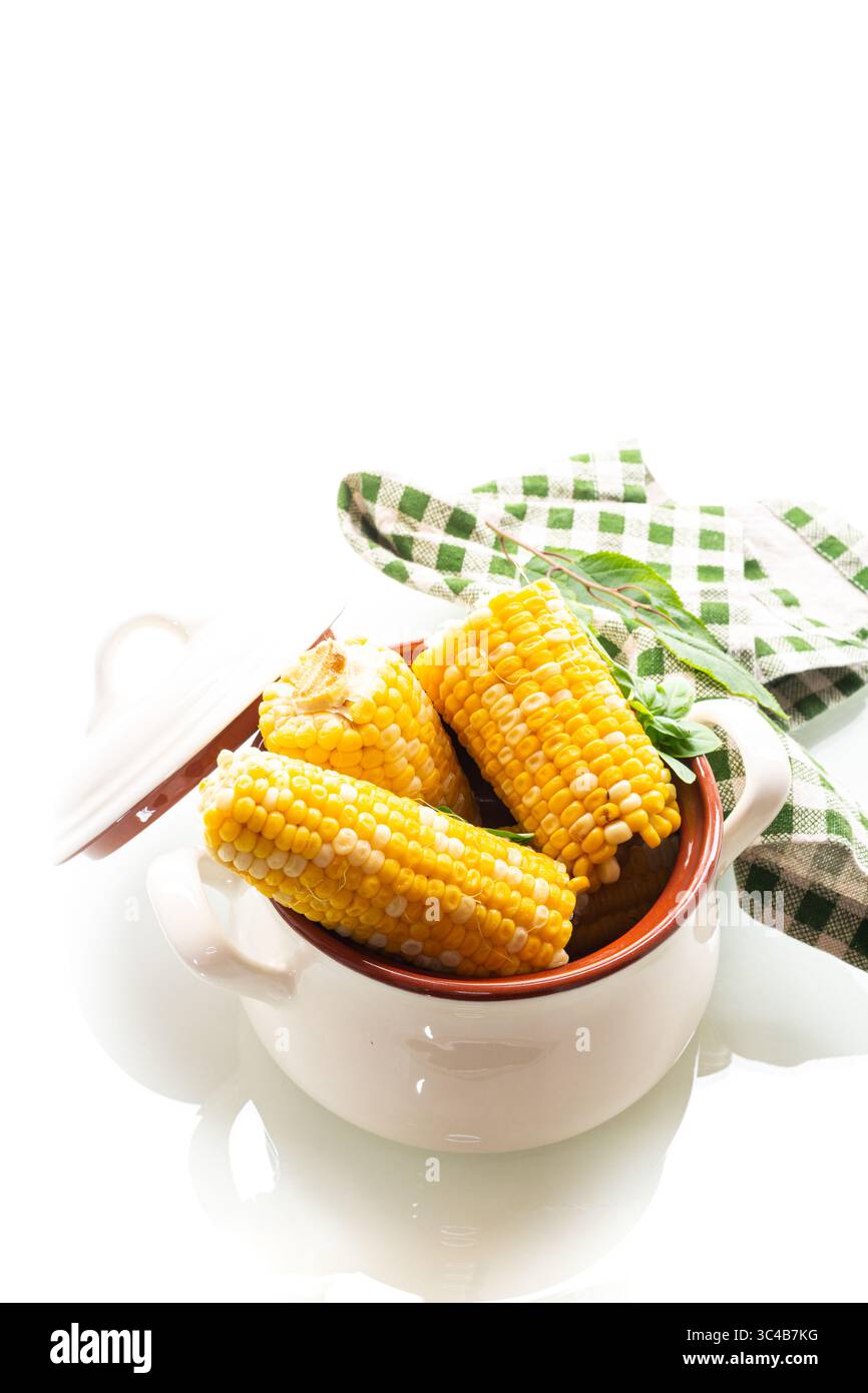 Two boiled corn cobs with dill on a white background. Stock Photo