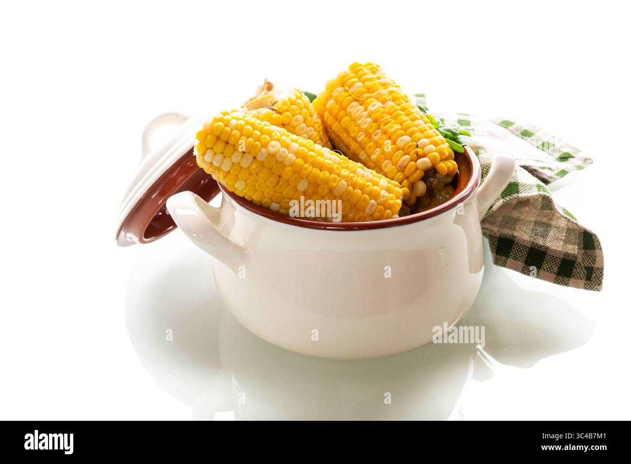 Two boiled corn cobs with dill on a white background. Stock Photo