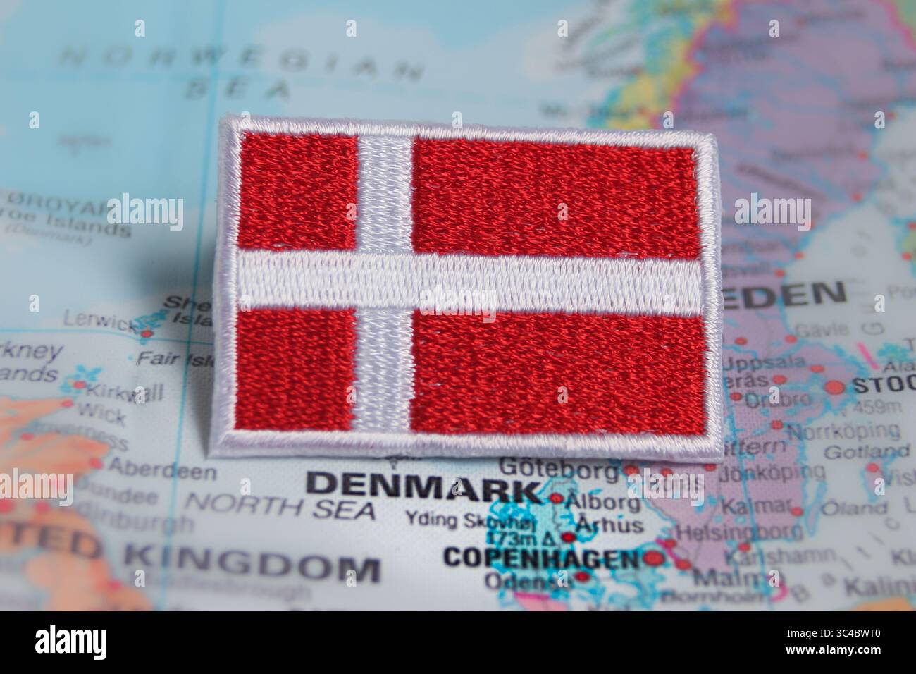 Eco-friendly embroidered Denmark flag on world map, placed precisely over Denmark. Perfect for sustainable travel and Nordic tourism themes. Stock Photo