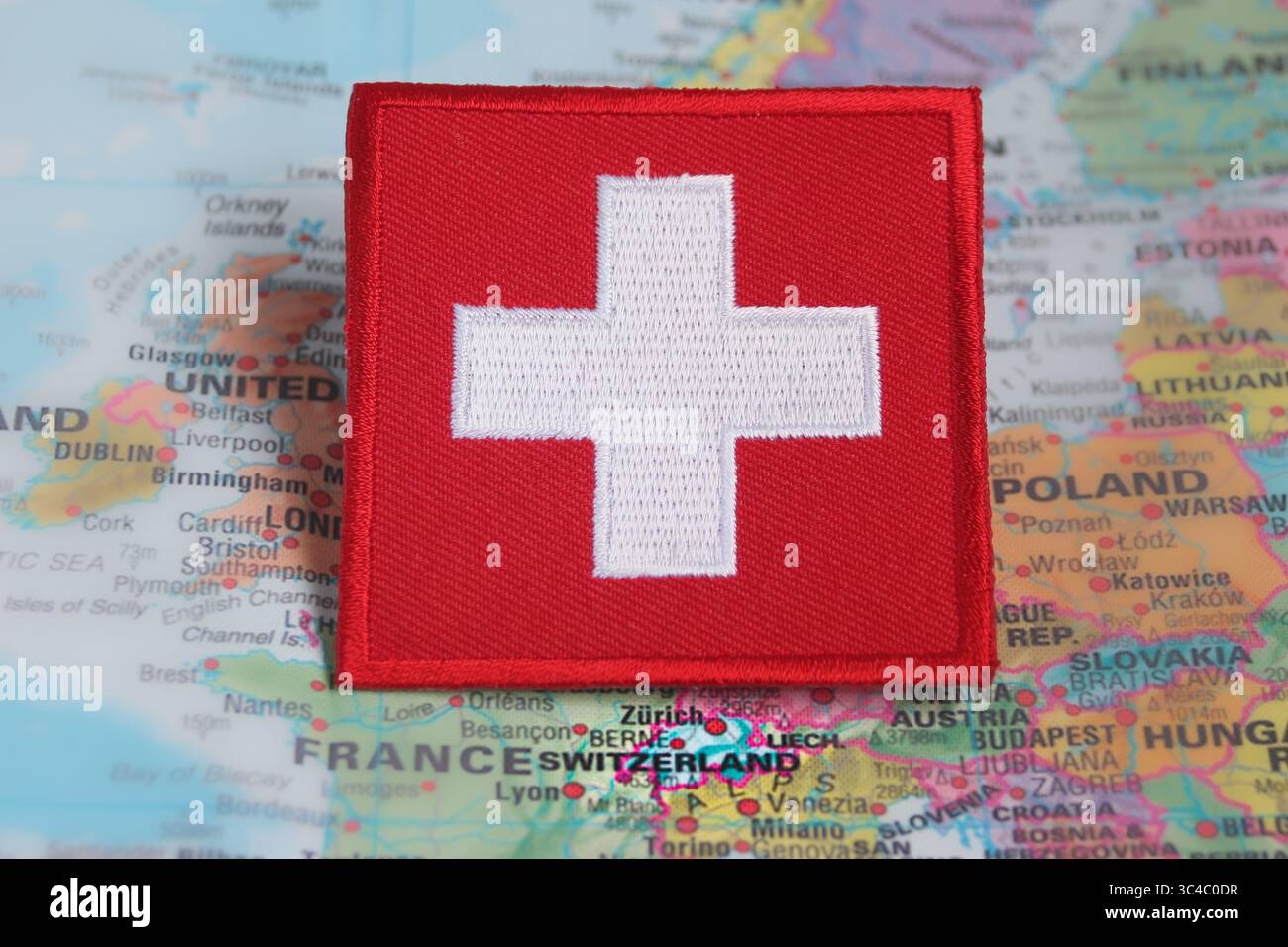 Eco-style embroidered Swiss flag patch placed on Europe’s map over Switzerland, symbolizing green travel, sustainability, and responsible tourism. Stock Photo