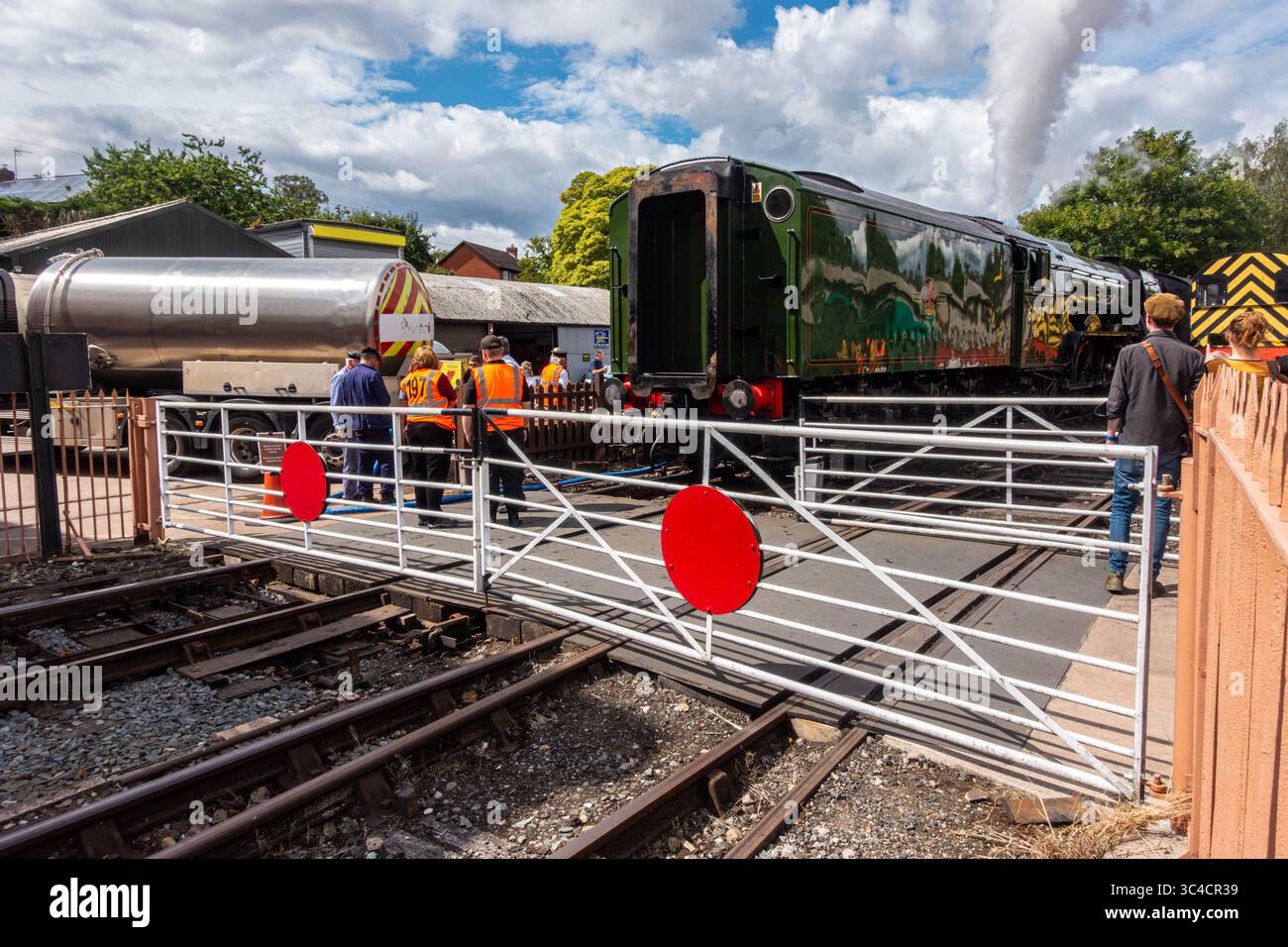 Flying Scotsman in steam stands just beyond a level crossing at