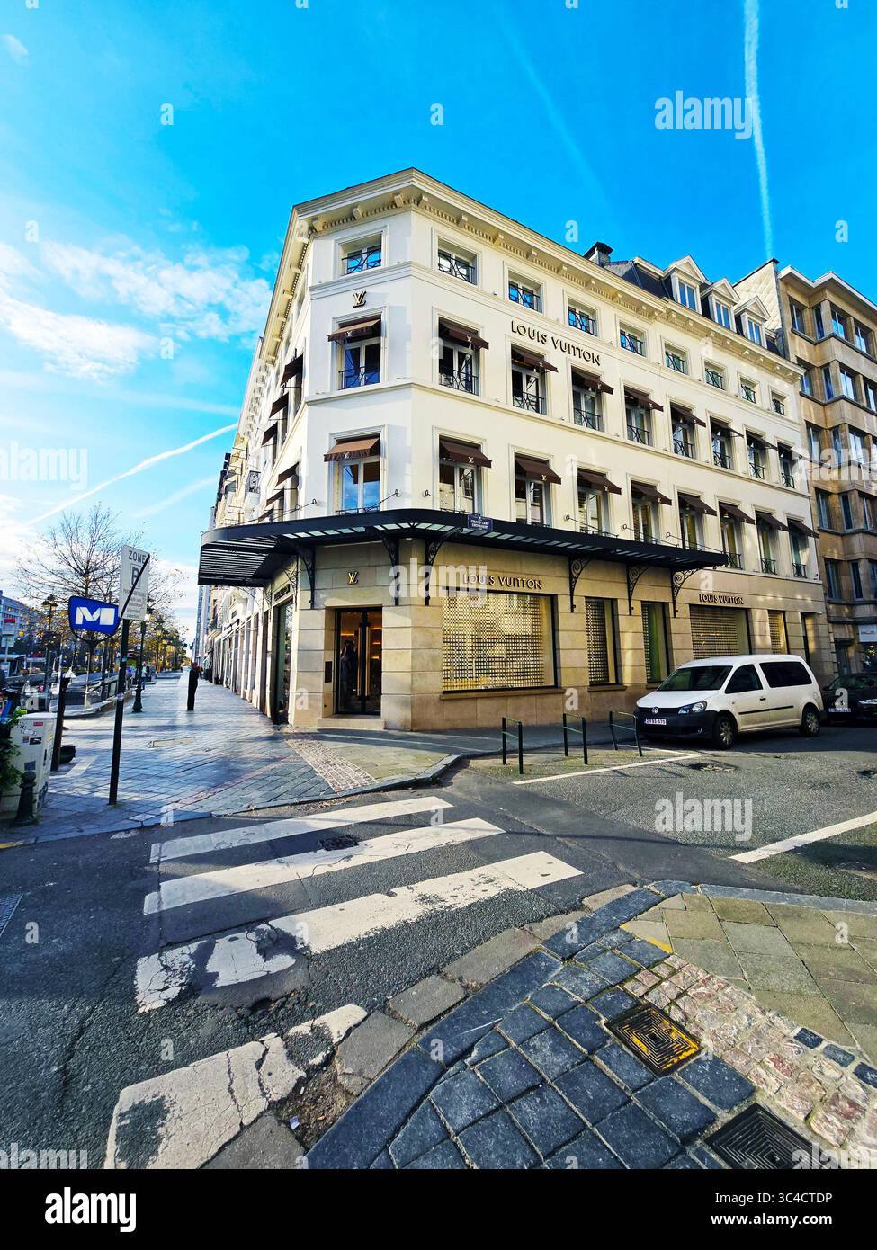 Wide-angle view of buildings and shops on a corner in the Brussels shopping district under a bright blue sky. - Smartphone Captured Stock Image