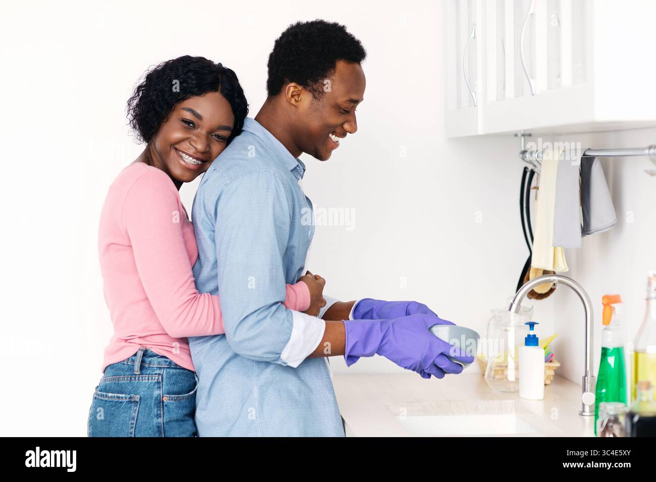 Black woman hugging her husband washing dishes Stock Photo - Alamy